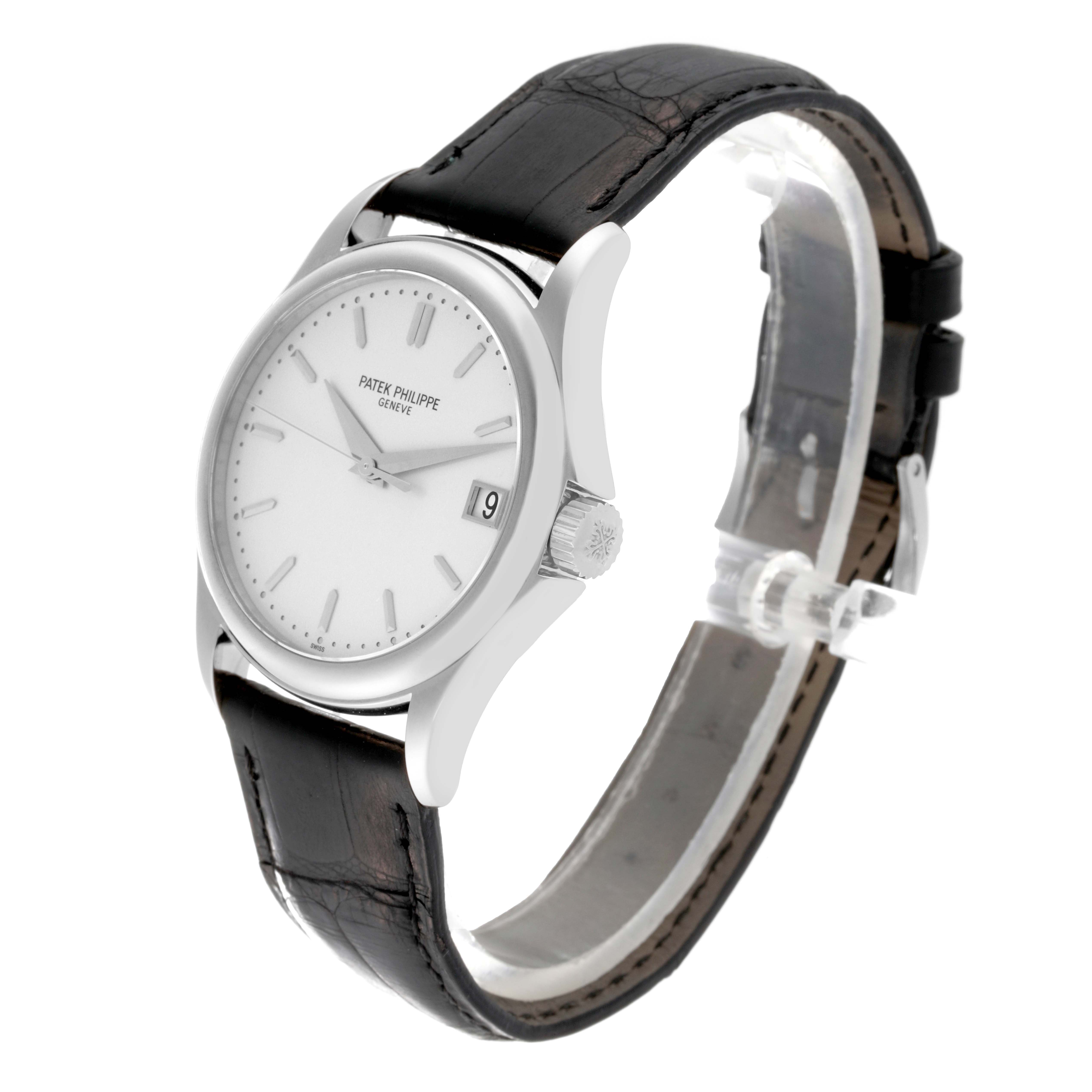 The image shows a Patek Philippe Calatrava 5127G-001 Men's White Gold Silver Dial 5127G-001 Men's White Gold Silver Dial watch at a three-quarter angle, featuring a white dial, black strap, and date window.