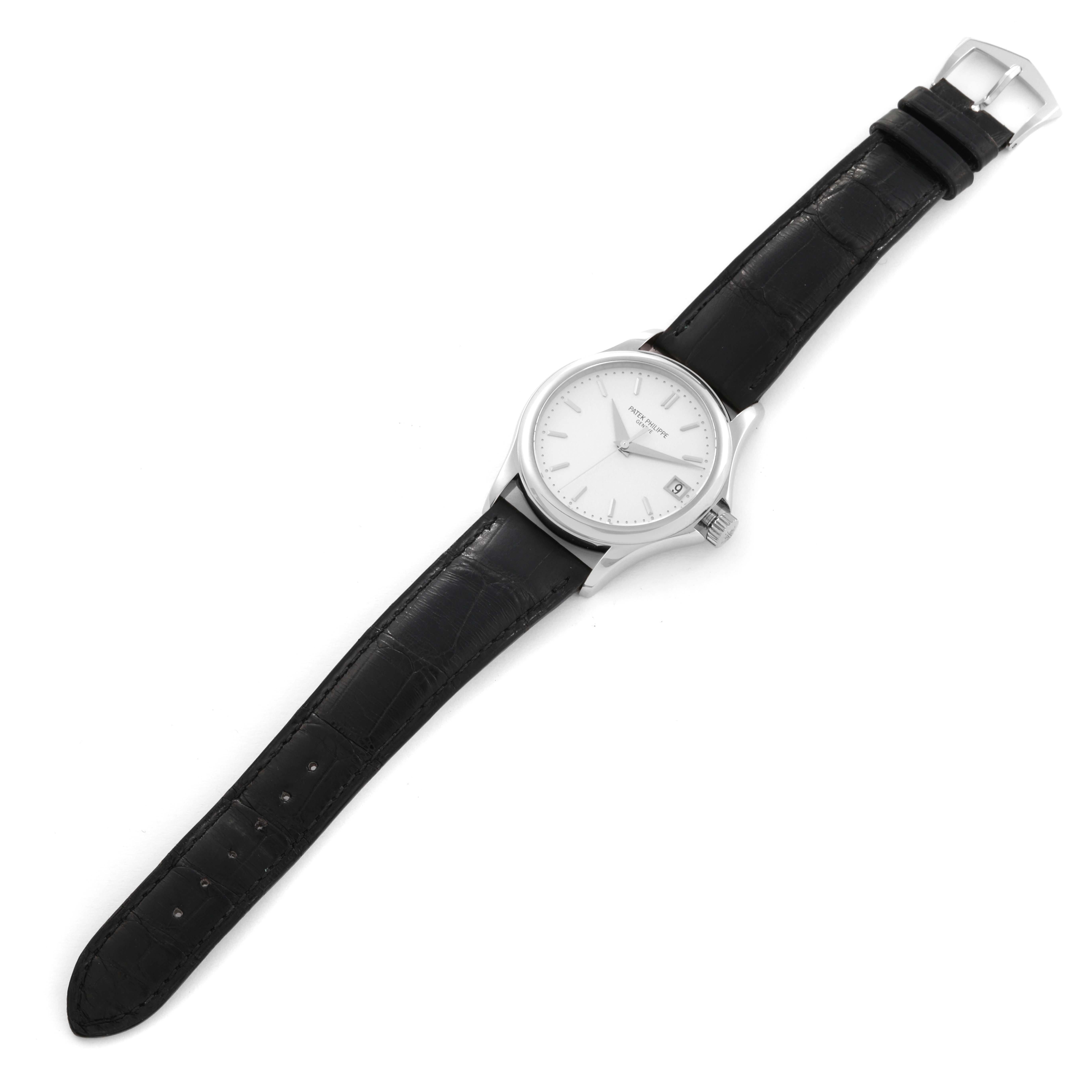The image shows a Patek Philippe Calatrava 5127G-001 Men's White Gold Silver Dial 5127G-001 Men's White Gold Silver Dial watch at an angled view, displaying its black leather strap, buckle, and white dial.