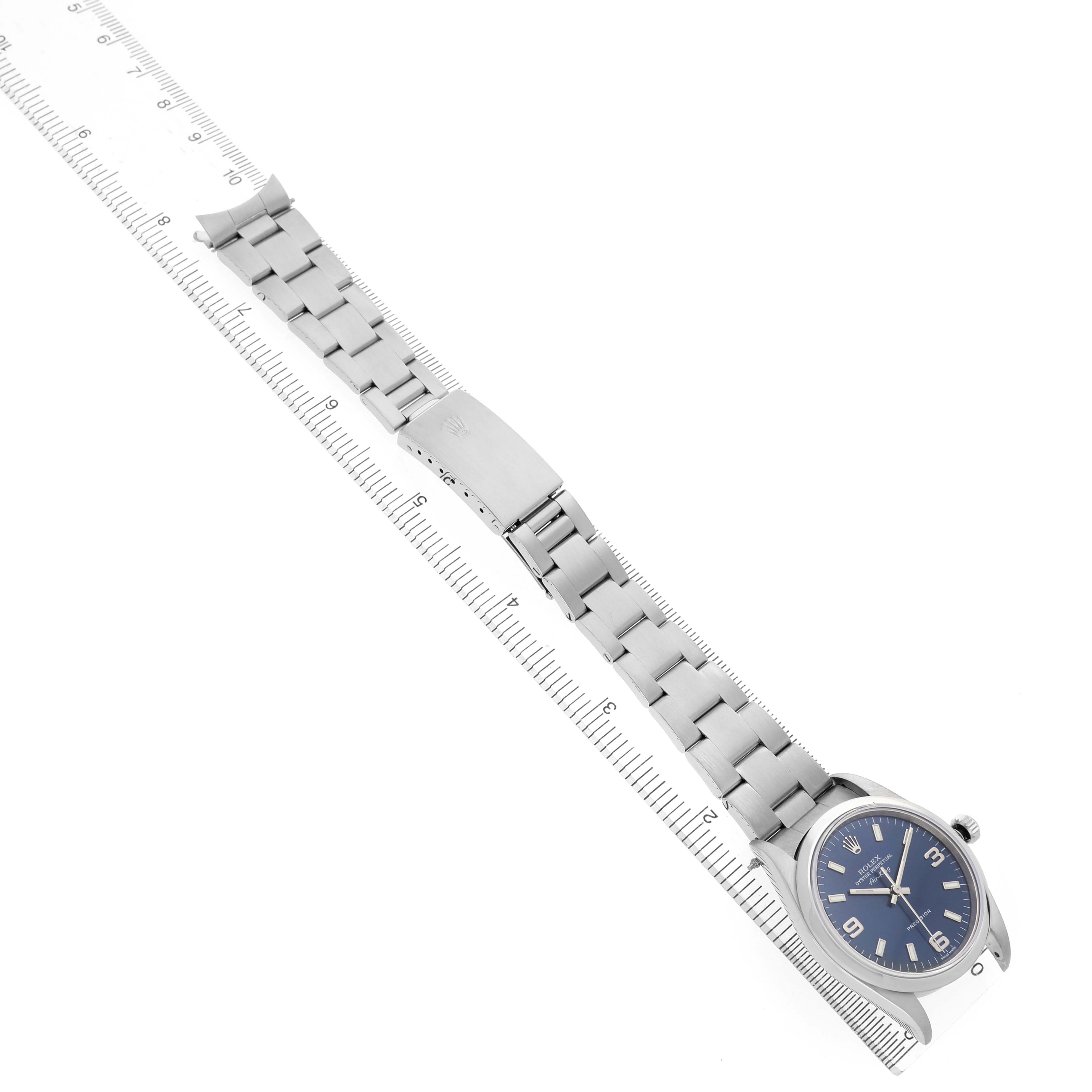 The Rolex Air-King 14000 Men's Stainless Steel Black Dial watch is shown from a top angle, featuring its face, bezel, bracelet, and clasp placed beside a ruler for scale.