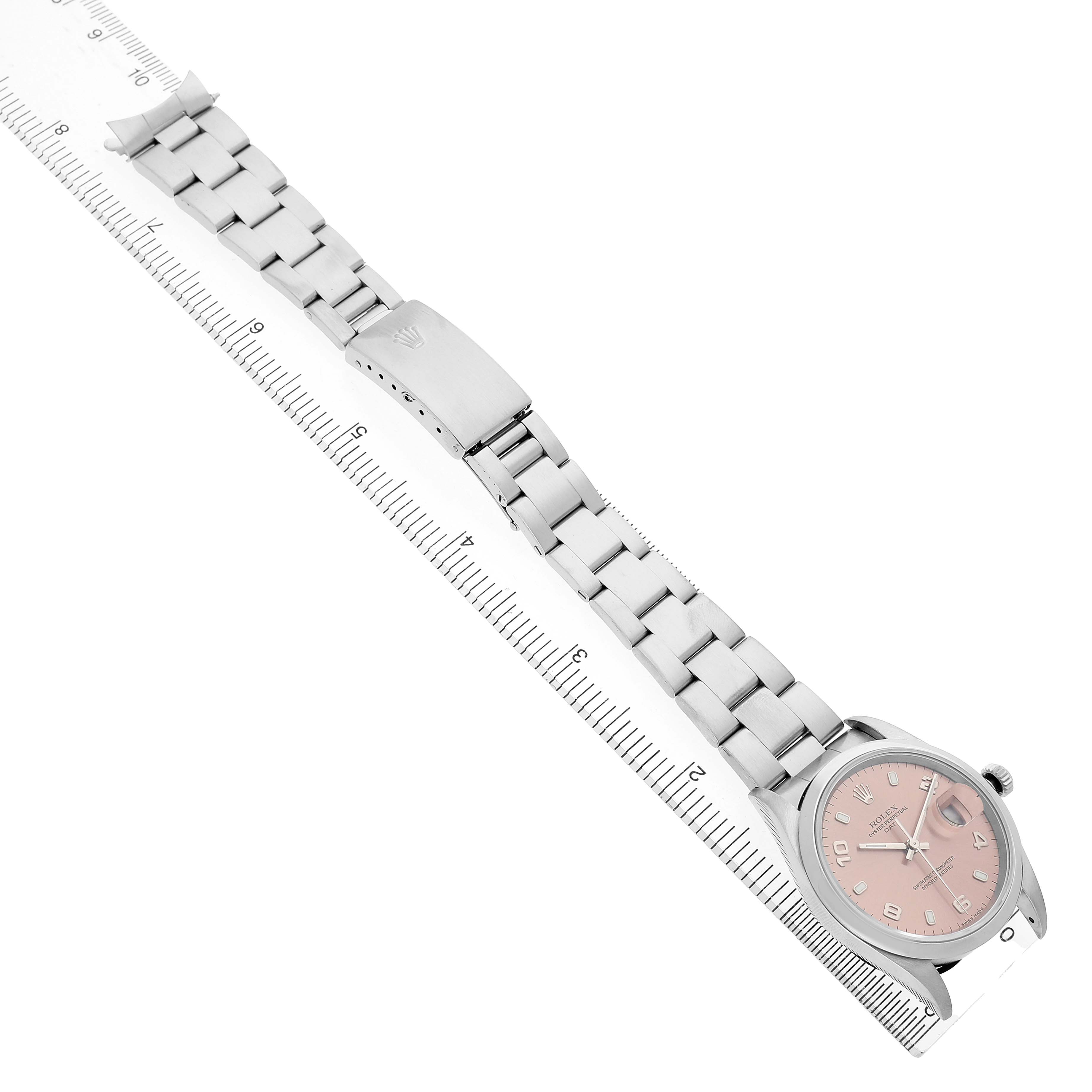 The Rolex Date 15200 Men's Stainless Steel Pink Dial watch is displayed at an angled view, showing the face, bracelet, and clasp using a measuring ruler for scale.