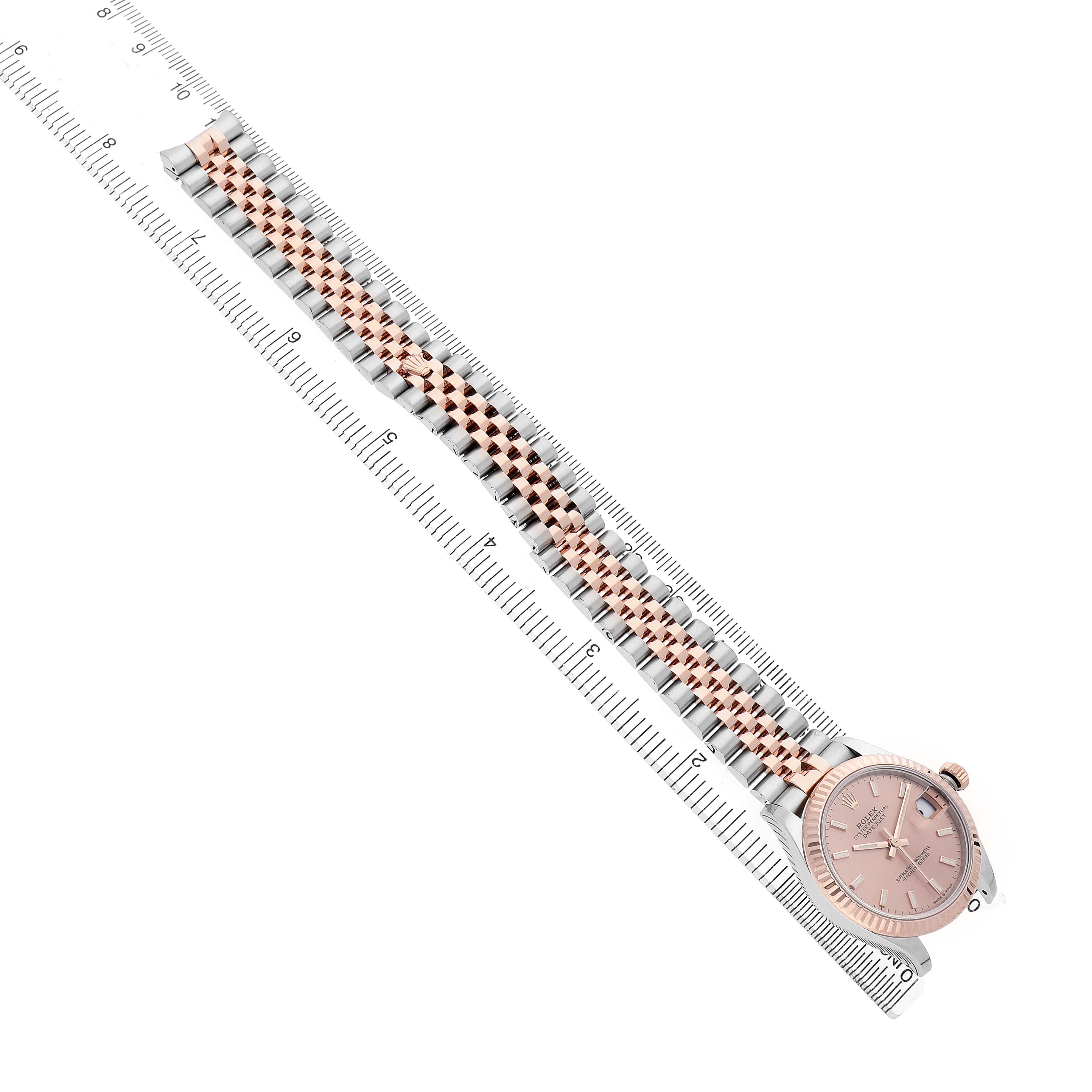 The Rolex Mid-Size 278271 Women's Steel and Gold (two tone) Pink Dial watch is shown from an overhead angle, displaying its full bracelet and face alongside a ruler for scale.