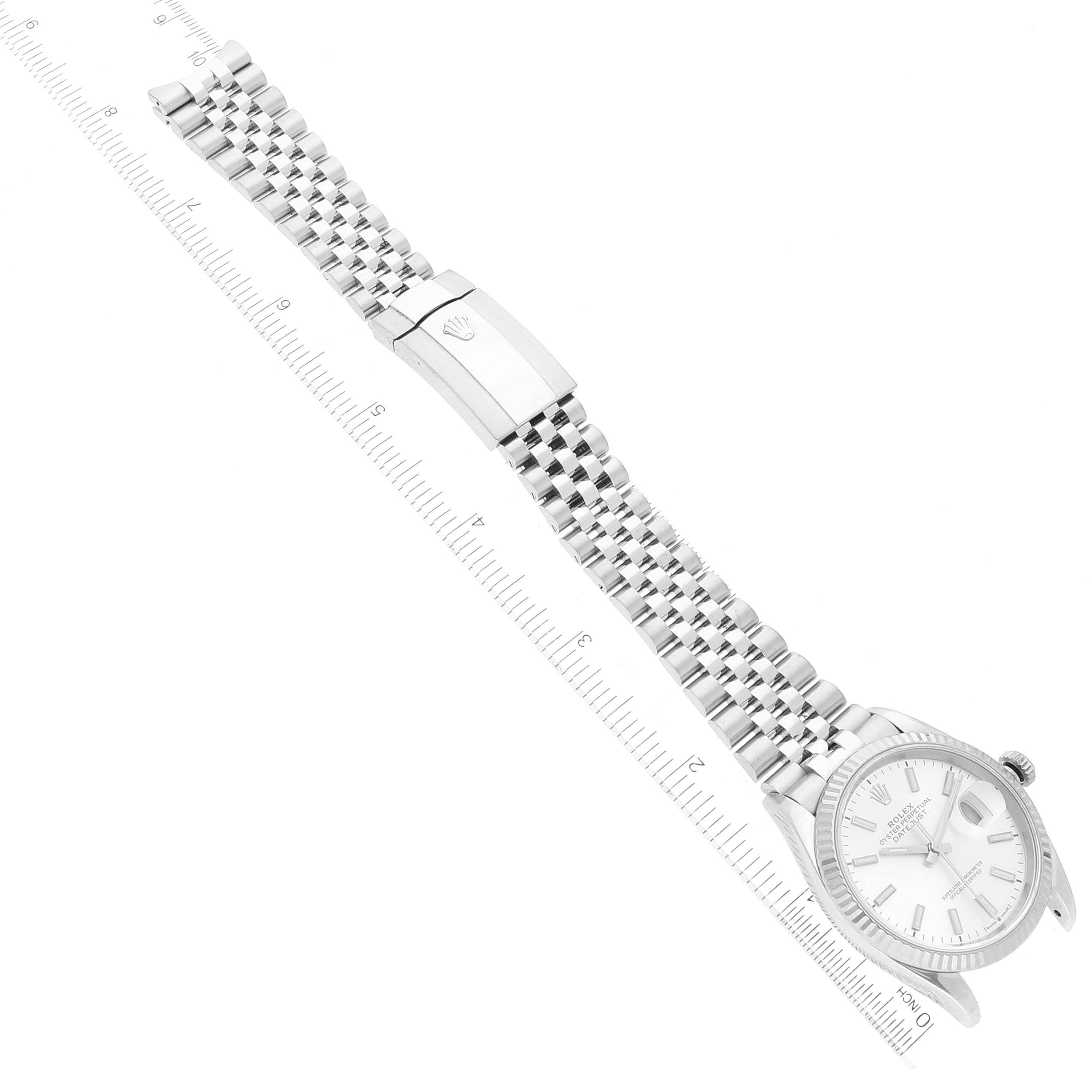 The image shows an overhead view of a Rolex Datejust 126234 Men's Stainless Steel Silver Dial 126234 Men's Stainless Steel Silver Dial watch with its face, bracelet, and clasp, placed next to a ruler for scale.