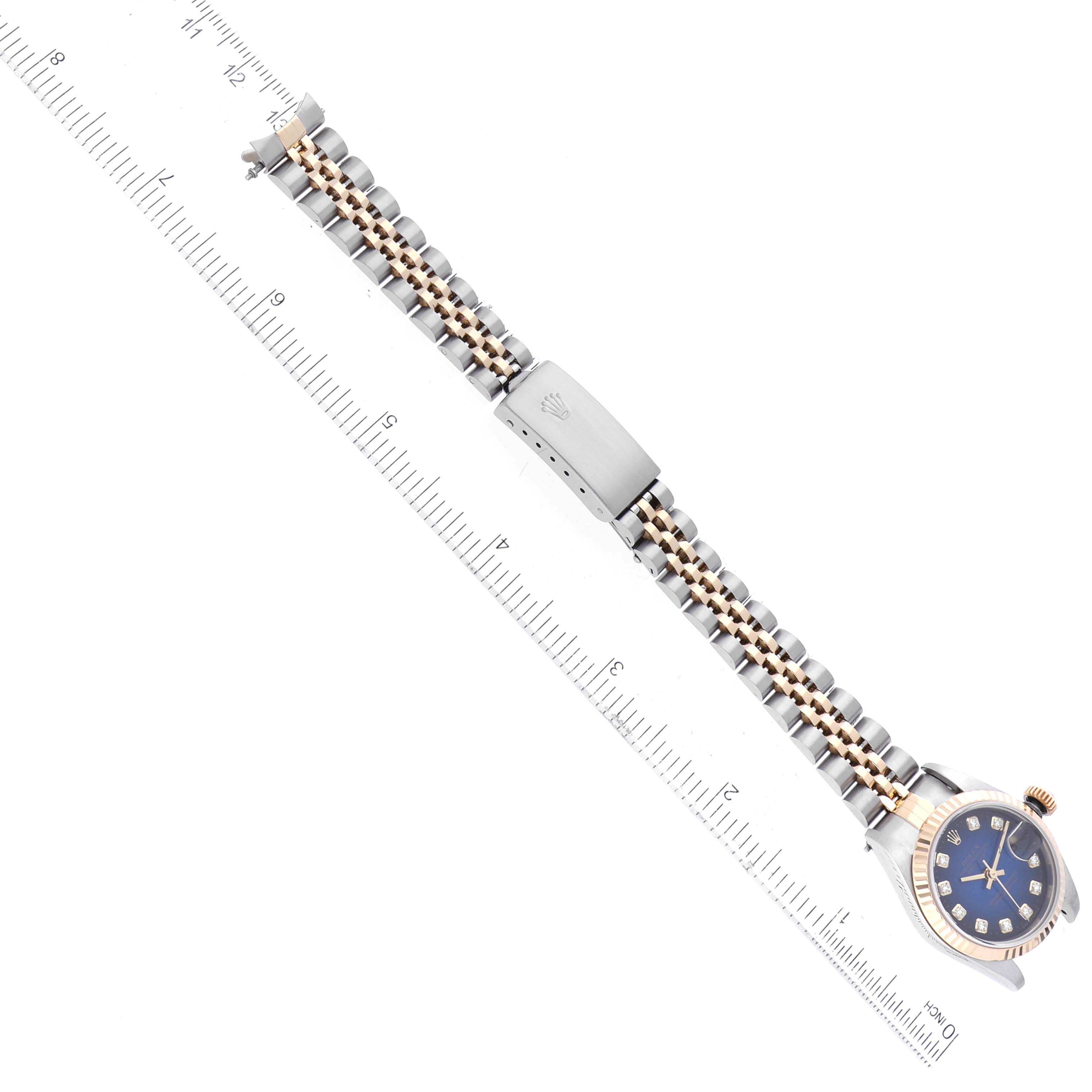 The image shows the Rolex Datejust 79173 Women's Steel and Gold (two tone) Blue Dial 79173 Women's Steel and Gold (two tone) Blue Dial watch laid flat with its bracelet extended, alongside a ruler for size indication.