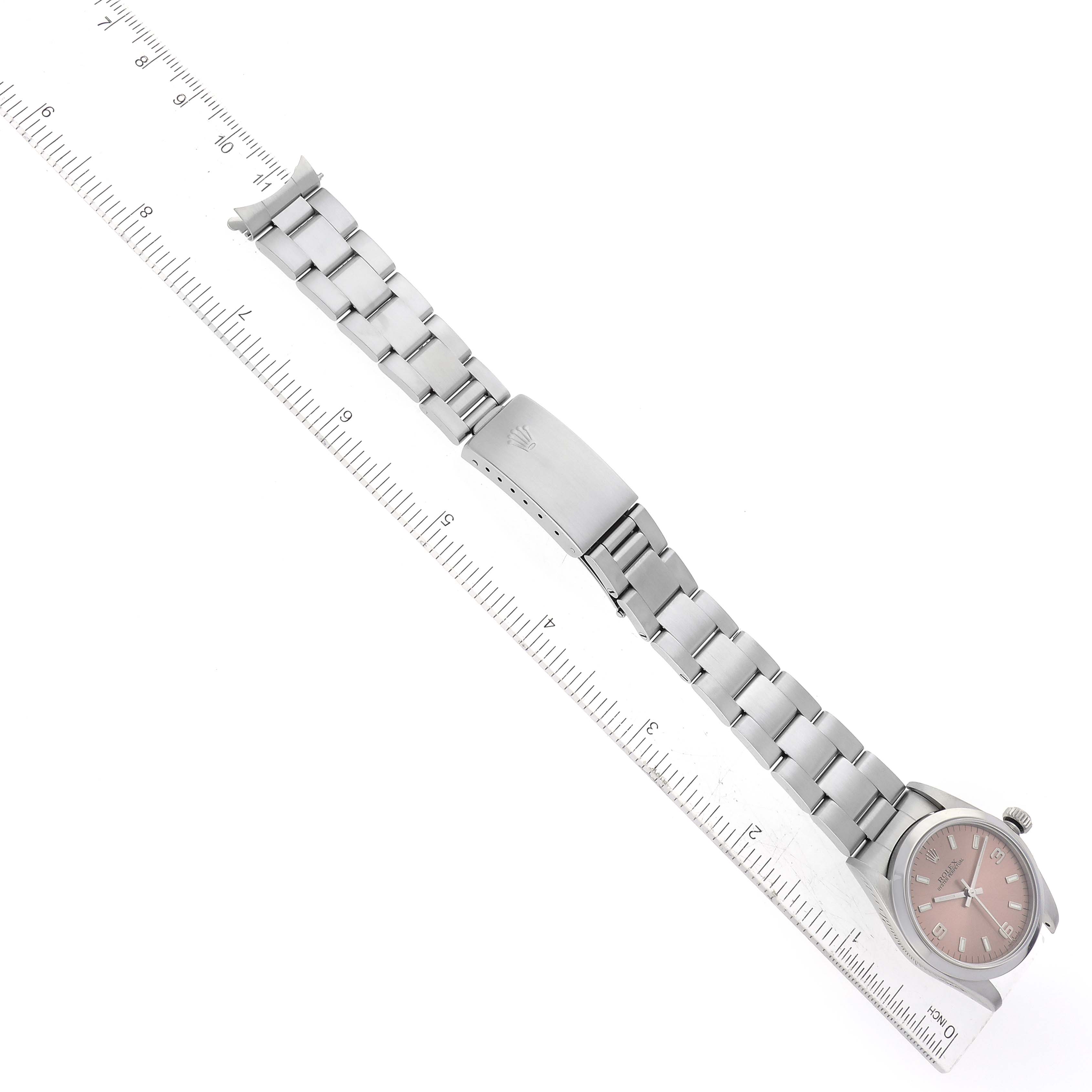 The image shows the top view of a Rolex Mid-Size 77080 Women's Stainless Steel Pink Dial 77080 Women's Stainless Steel Pink Dial watch, displaying the face, bracelet, and clasp, placed alongside a ruler for measurement.