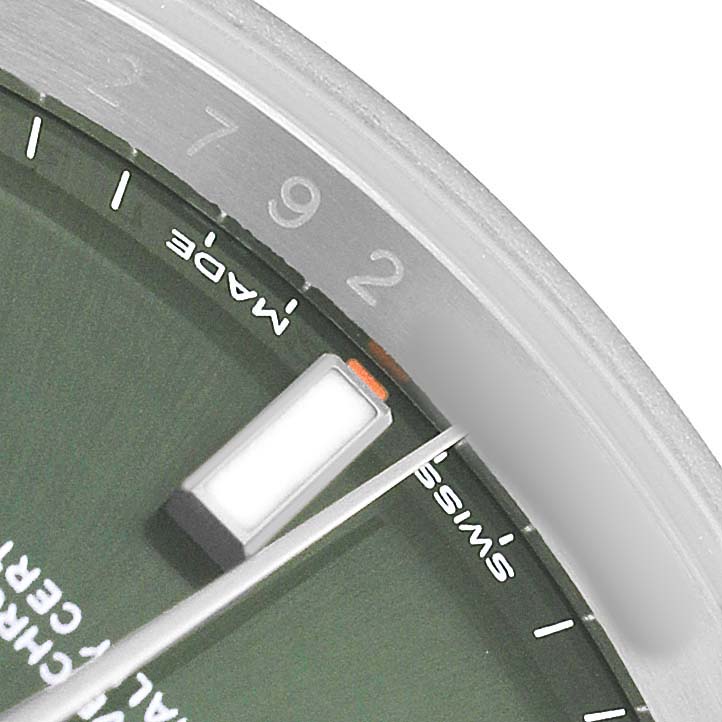 The image shows a close-up of the dial and bezel of a Rolex Oyster Perpetual 114200 Men's Stainless Steel Green Dial watch, highlighting the markers and part of the minute hand.