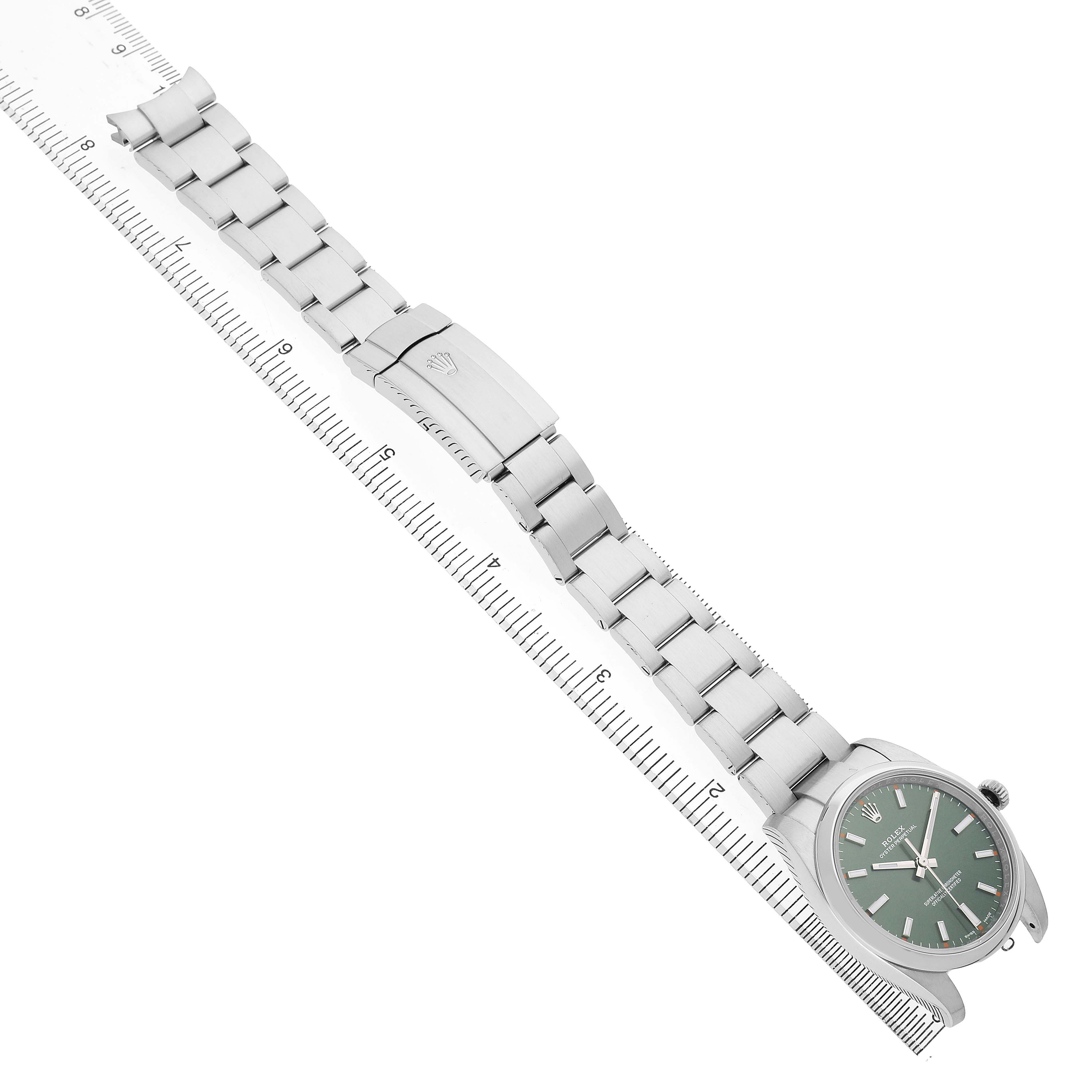 The Rolex Oyster Perpetual 114200 Men's Stainless Steel Green Dial watch is shown from a top-down angle, displaying the bracelet, clasp, and dial.