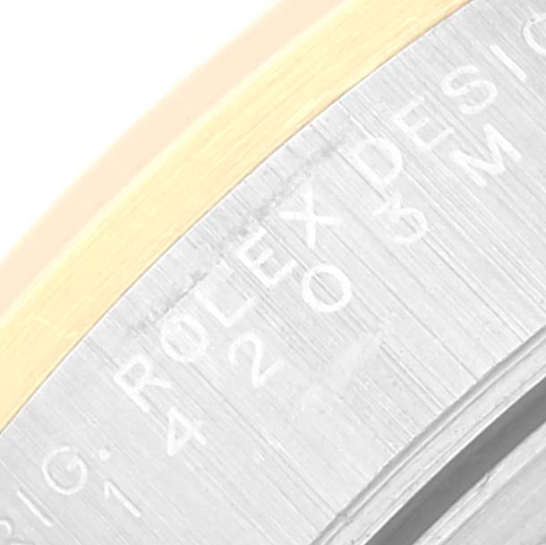 This close-up angle shows part of the bezel and casing of a Rolex Oyster Perpetual 14203 Men's Steel and Gold (two tone) Grey Dial 14203 Men's Steel and Gold (two tone) Grey Dial watch with "ROLEX DESIGN" engraved.
