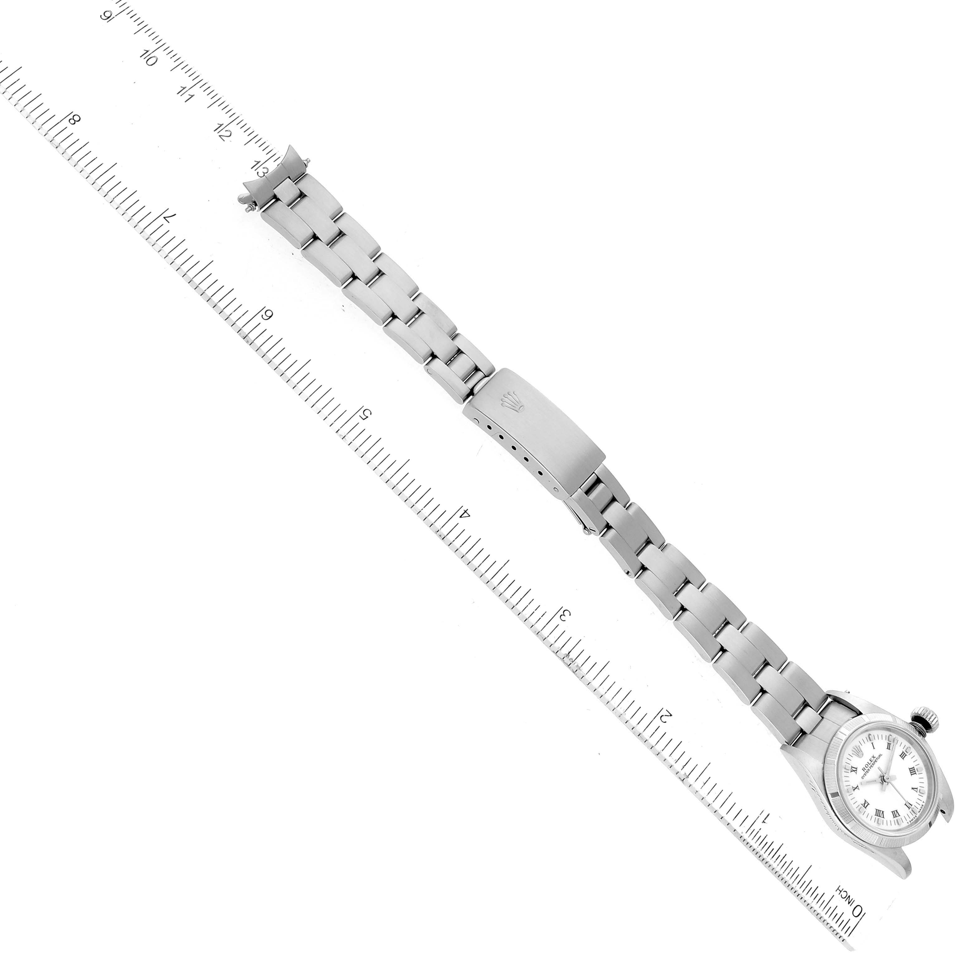 The image shows the Rolex Oyster Perpetual 67230 Women's Stainless Steel White Dial 67230 Women's Stainless Steel White Dial watch positioned diagonally with the bracelet fully extended and a ruler on the side for scale.