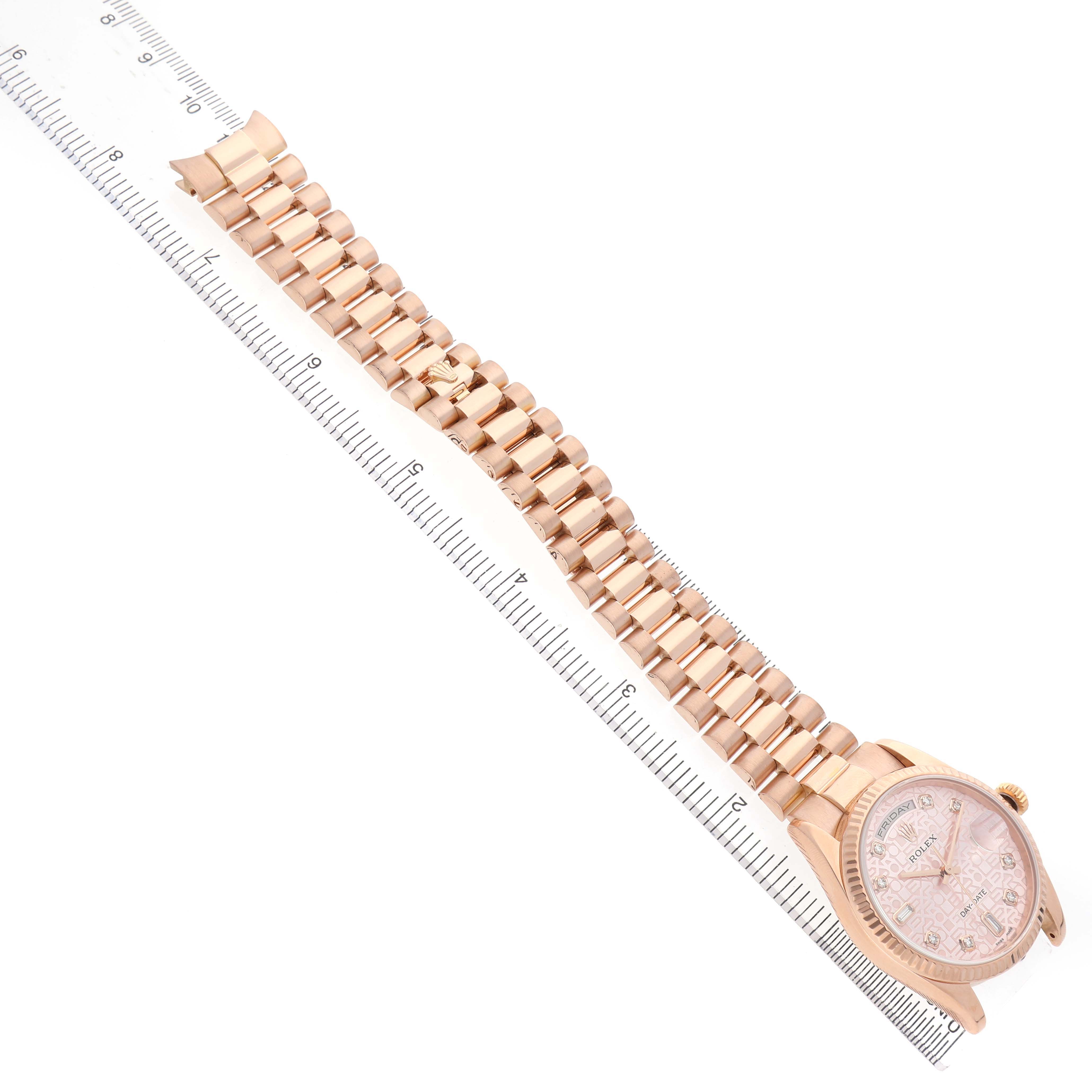 The Rolex President 118235 Men's Rose Gold Pink Dial model watch is shown in full view, displaying the face, case, and entire bracelet laid next to a ruler for scale.