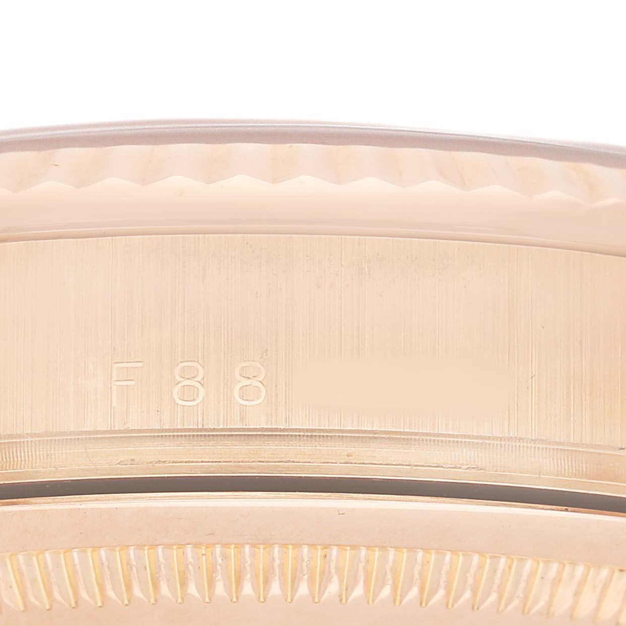 The image shows the edge and part of the bezel of a Rolex President 118235 Men's Rose Gold Pink Dial watch, featuring engraved numbers.
