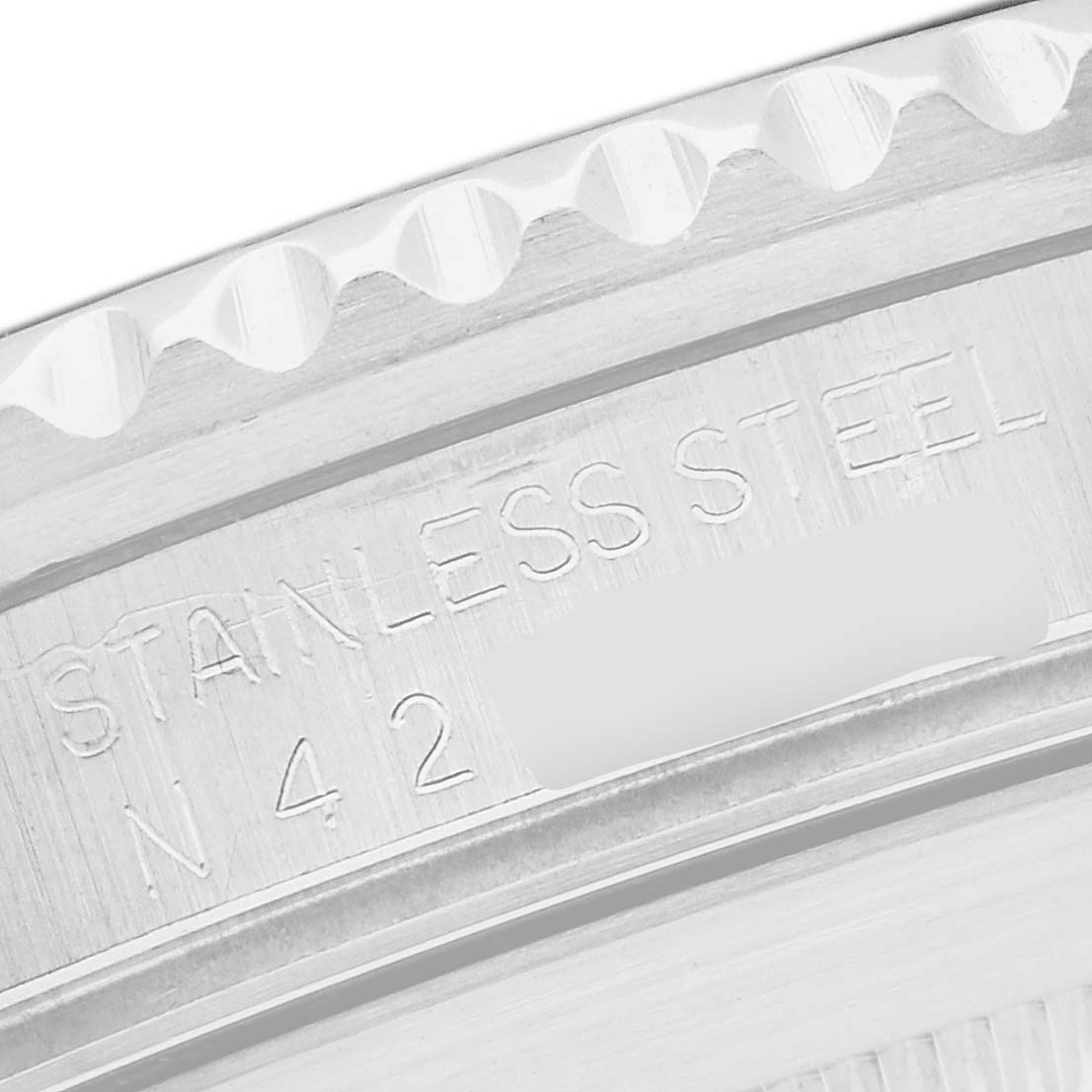 The image shows a close-up of the stainless steel bezel edge with engraved markings on a Rolex Submariner, model 16610.