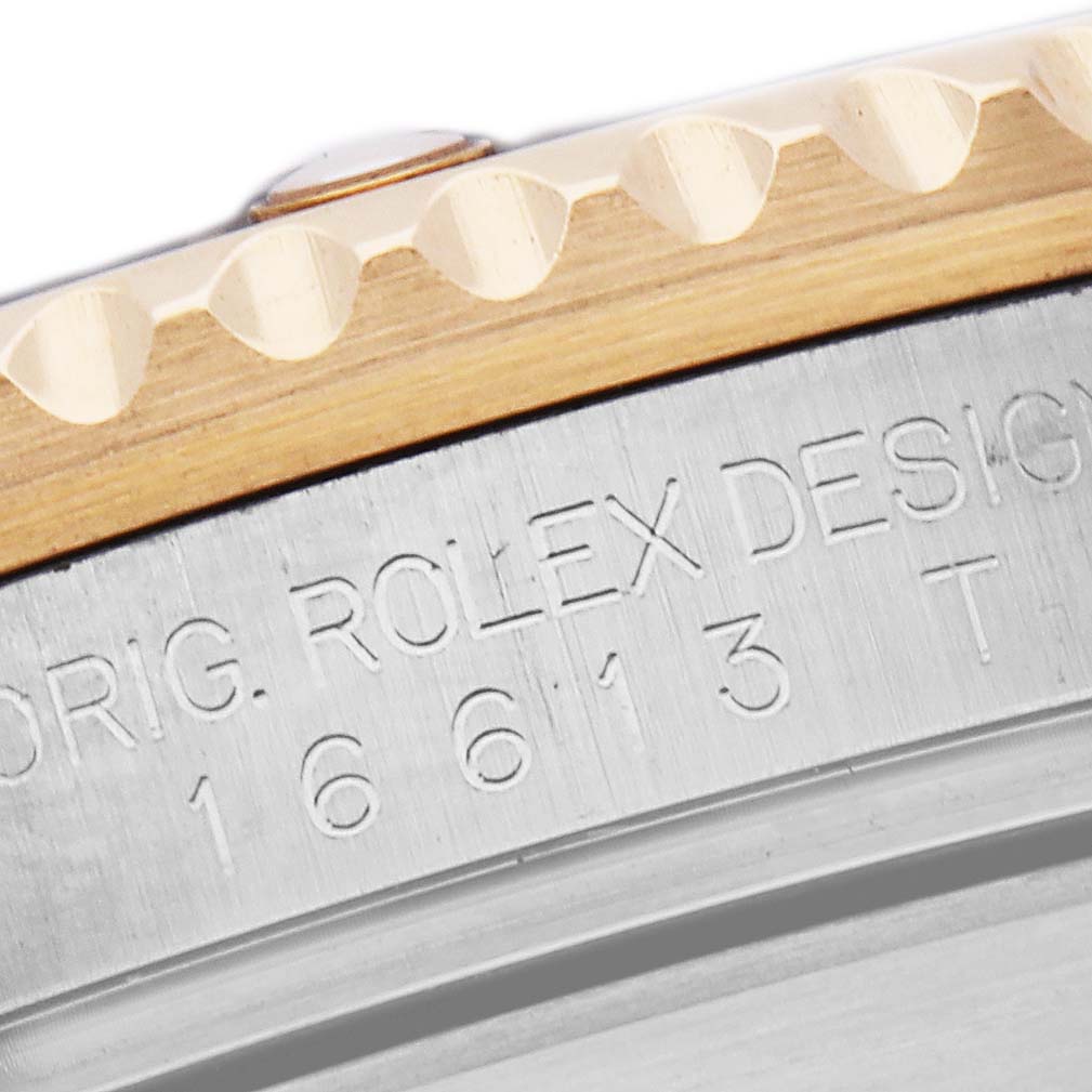 The image shows a close-up of the bezel and engraved side of a Rolex Submariner, model number 16613, highlighting the design details.
