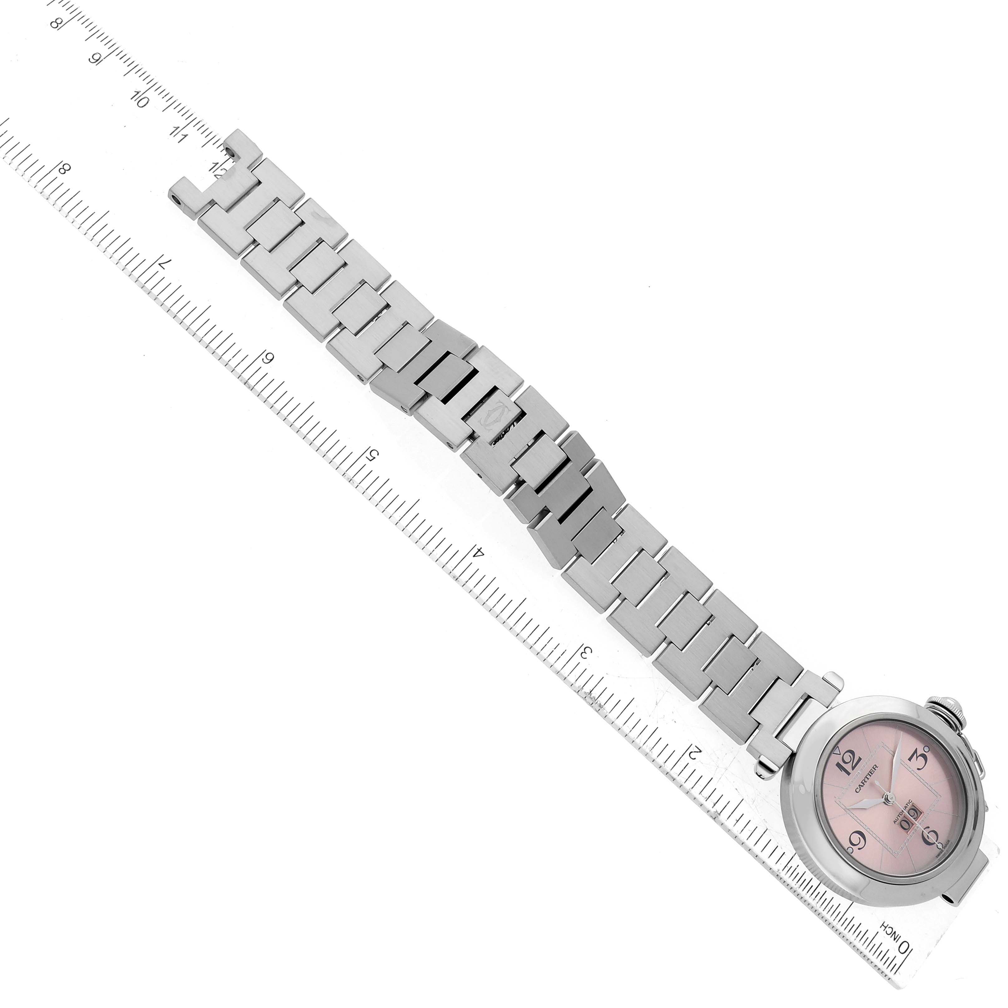 The Cartier Pasha W31058M7 Women's Stainless Steel Pink Dial W31058M7 Women's Stainless Steel Pink Dial watch is shown at an angle, laid flat with its metal bracelet fully extended beside a ruler.