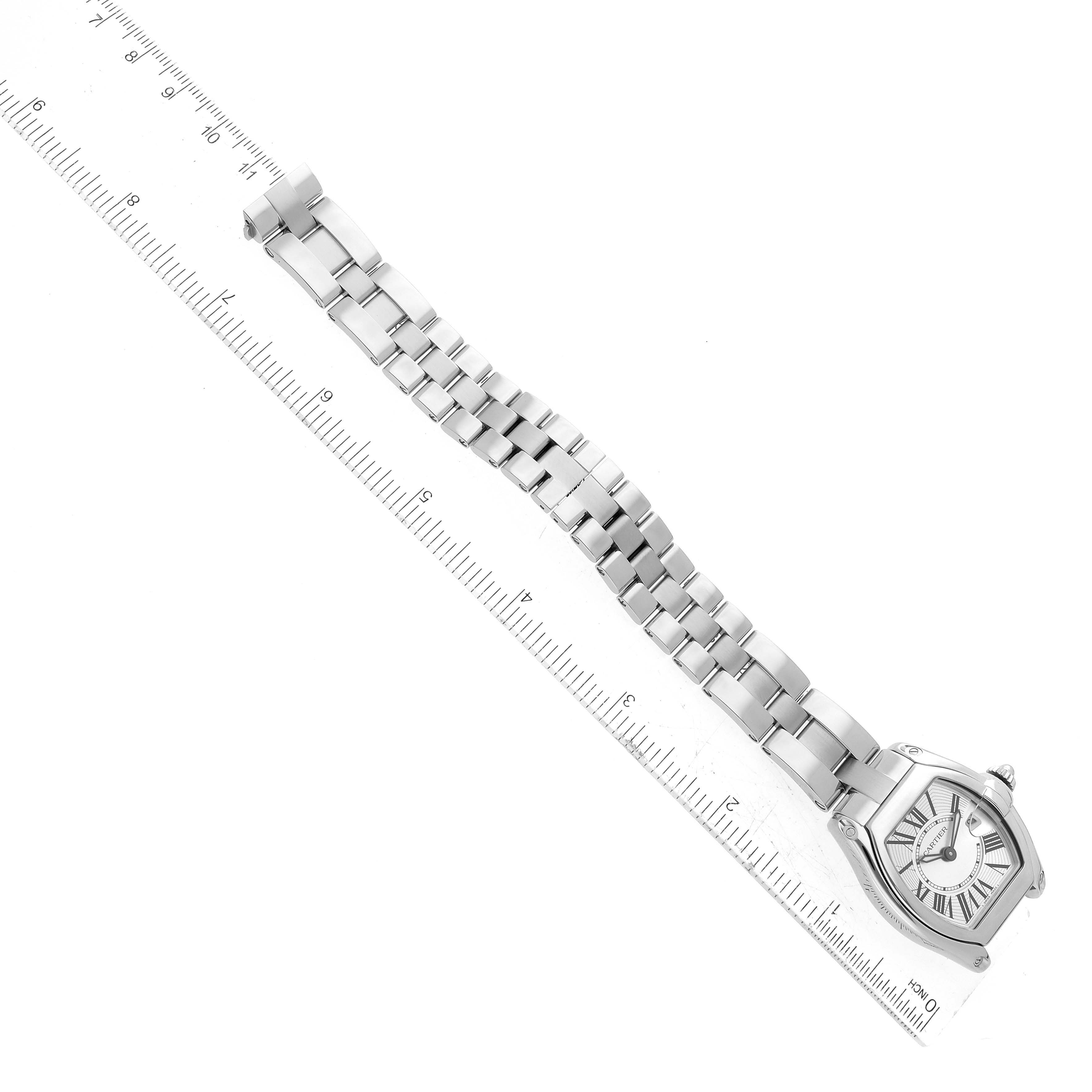 The image shows a top-down view of a Cartier Roadster W62016V3 Women's Stainless Steel Silver Dial W62016V3 Women's Stainless Steel Silver Dial watch with a metal bracelet aligned along a ruler.