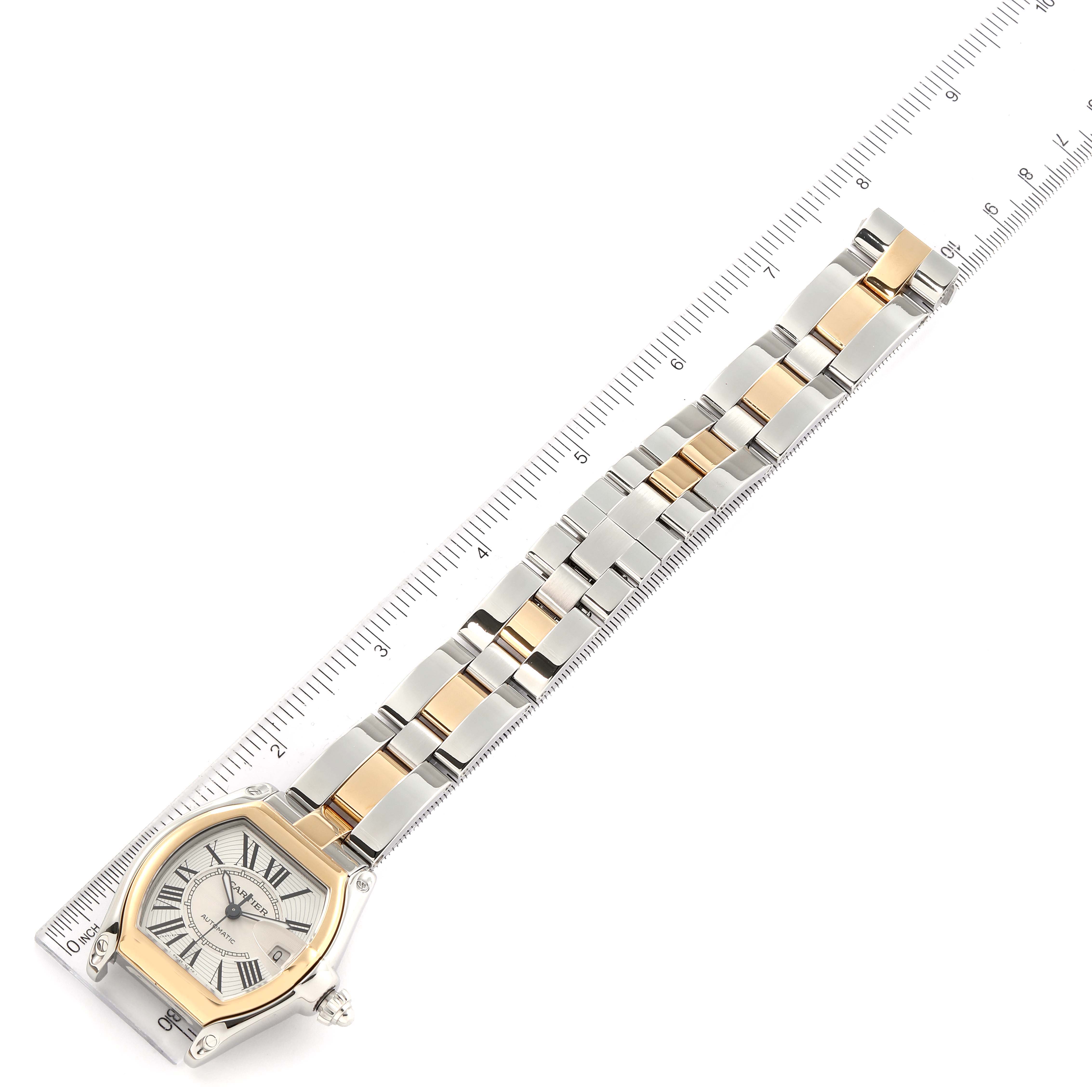 The image shows a top view of a Cartier Roadster W62031Y4 Men's Steel and Gold (two tone) Silver Dial W62031Y4 Men's Steel and Gold (two tone) Silver Dial watch, highlighting the face and the two-tone metal bracelet against a ruler.