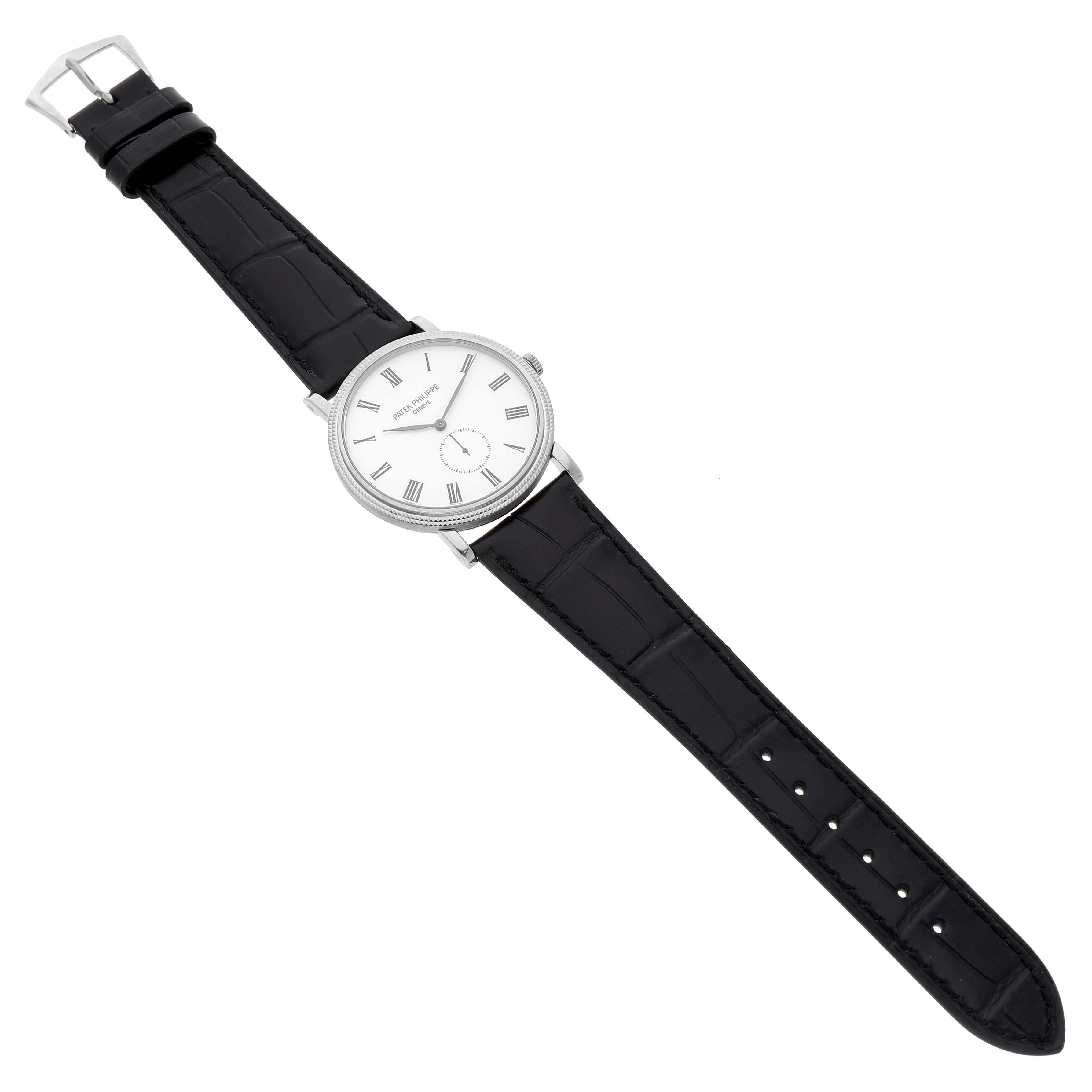 The Patek Philippe Calatrava 5116G-001 Men's White Gold White Dial watch is shown from a top-down angle, displaying its white dial, black leather strap, and silver buckle.