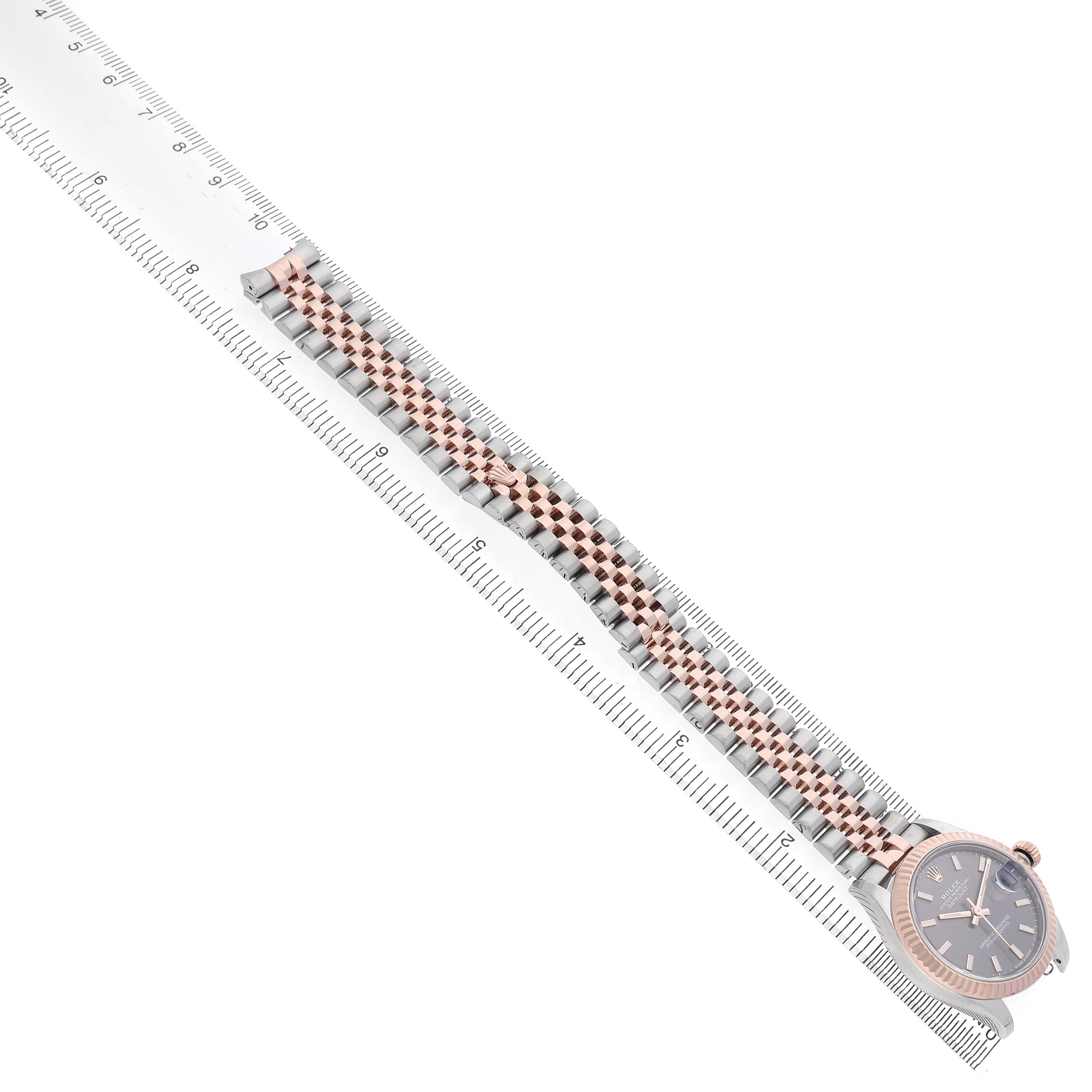 The Rolex Mid-Size 278271 Women's Steel and Gold (two tone) Grey Dial watch is displayed diagonally, featuring a detailed view of its bracelet and watch face alongside a ruler.