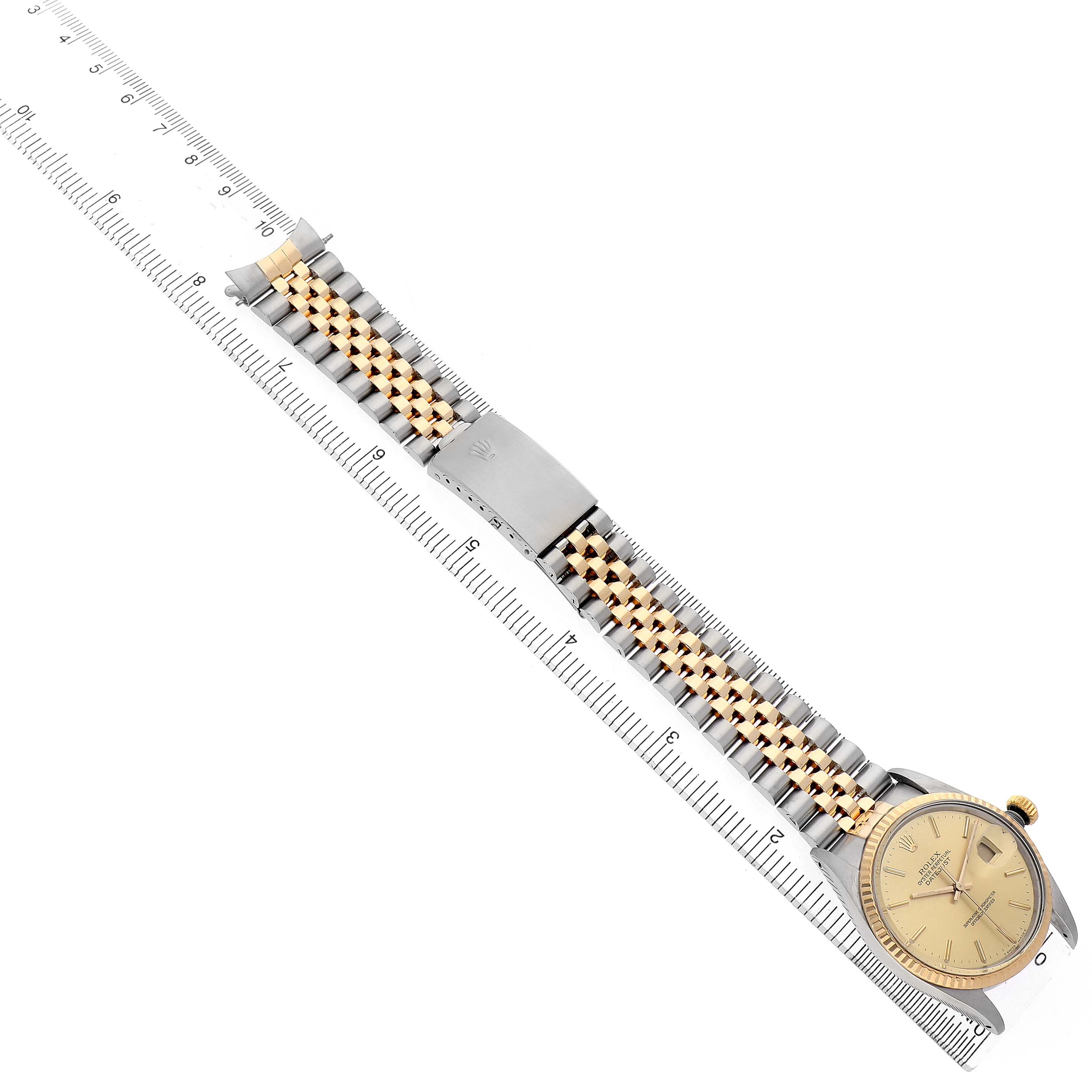 The image shows a diagonal top view of a Rolex Datejust 16013 Men's Steel and Gold (two tone) Champagne Dial watch, highlighting the bracelet, clasp, and face alongside a ruler.