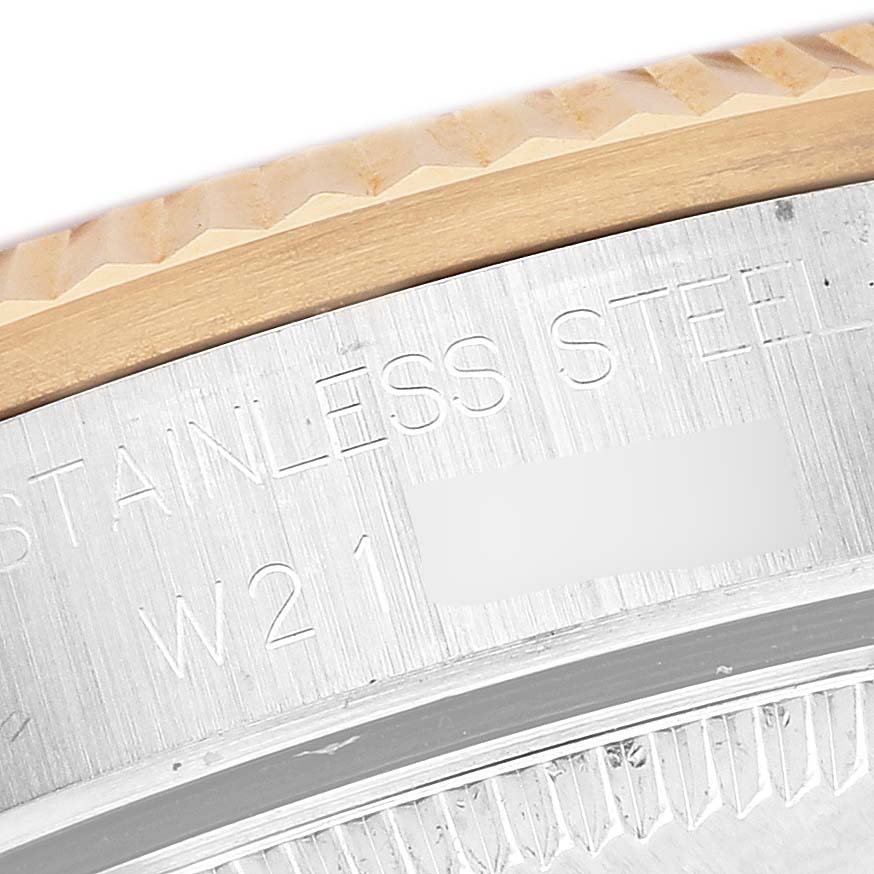 The image shows a close-up of the Rolex Mid-Size 68273 Women's Steel and Gold (two tone) Champagne Dial watch's fluted bezel and stainless steel case, highlighting engravings.
