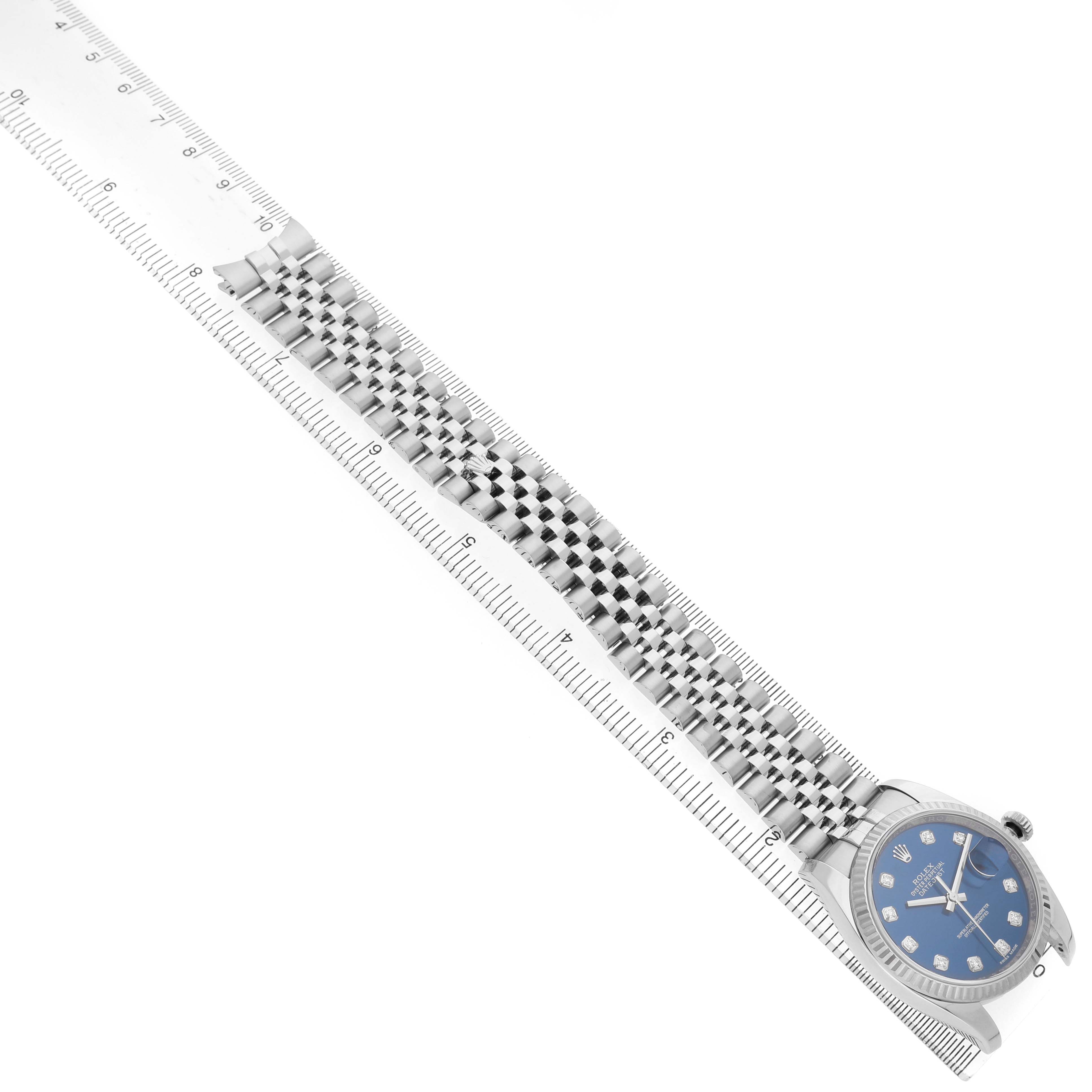 The image shows a Rolex Datejust 116234 Men's Stainless Steel Blue Dial watch at an angle, highlighting the bracelet and dial alongside a measuring ruler.