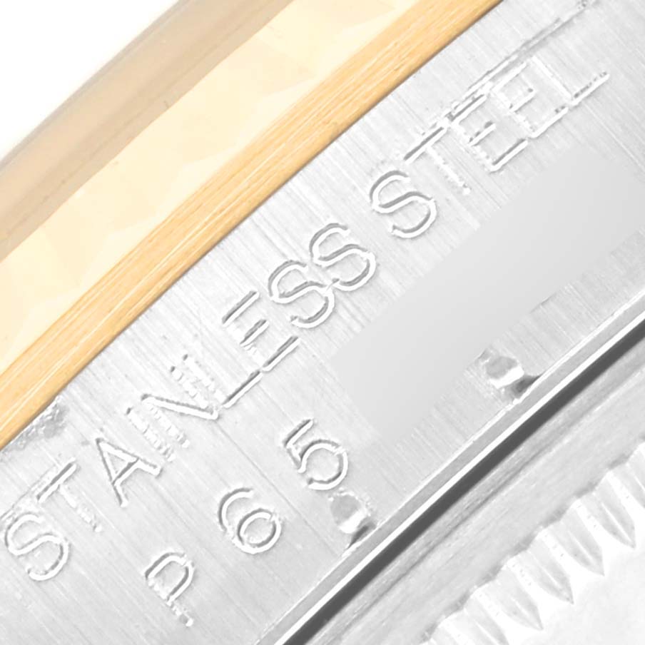 This image shows a close-up of the stainless steel case side of a Rolex Datejust 16233 Men's Steel and Gold (two tone) White Dial 16233 Men's Steel and Gold (two tone) White Dial watch with etched text details.