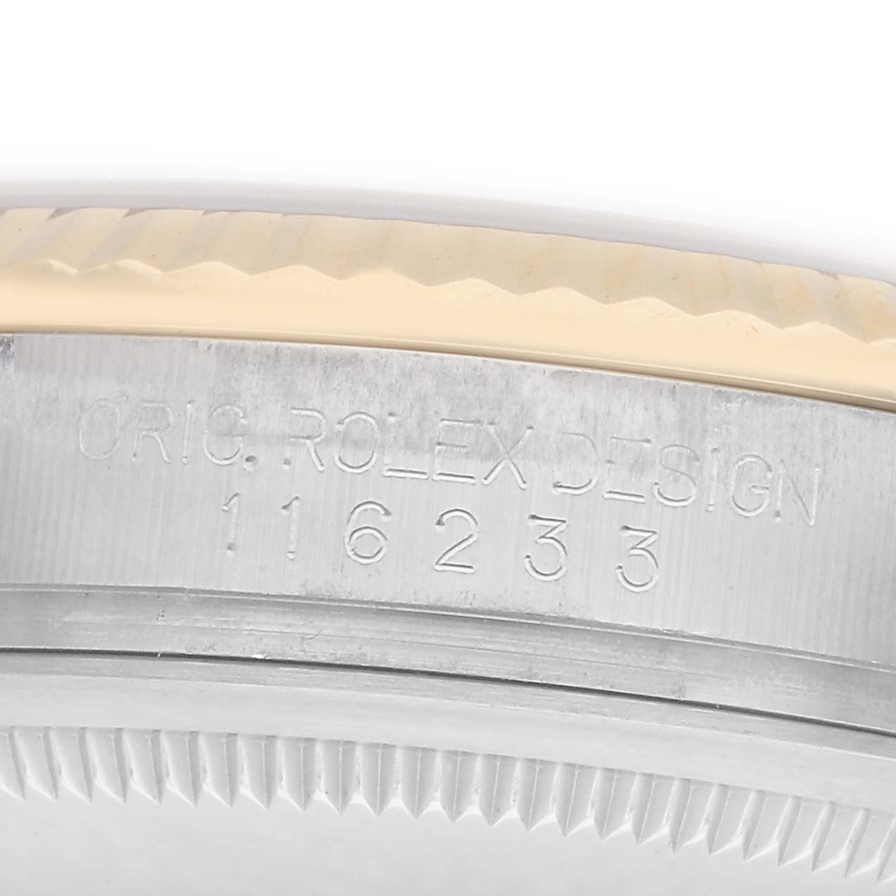 The image shows the side of the Rolex Datejust model 116233, focusing on the engraved "ORIG. ROLEX DESIGN 116233" and the edge of the fluted bezel.