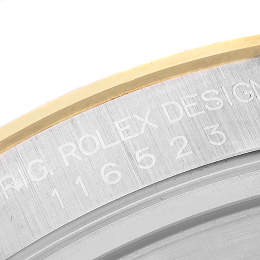 The image shows a close-up of the side engraving on the bezel of a Rolex Daytona 116523 Men
s Steel and Gold (two tone) Champagne Dial 116523 Men
s Steel and Gold (two tone) Champagne Dial watch.