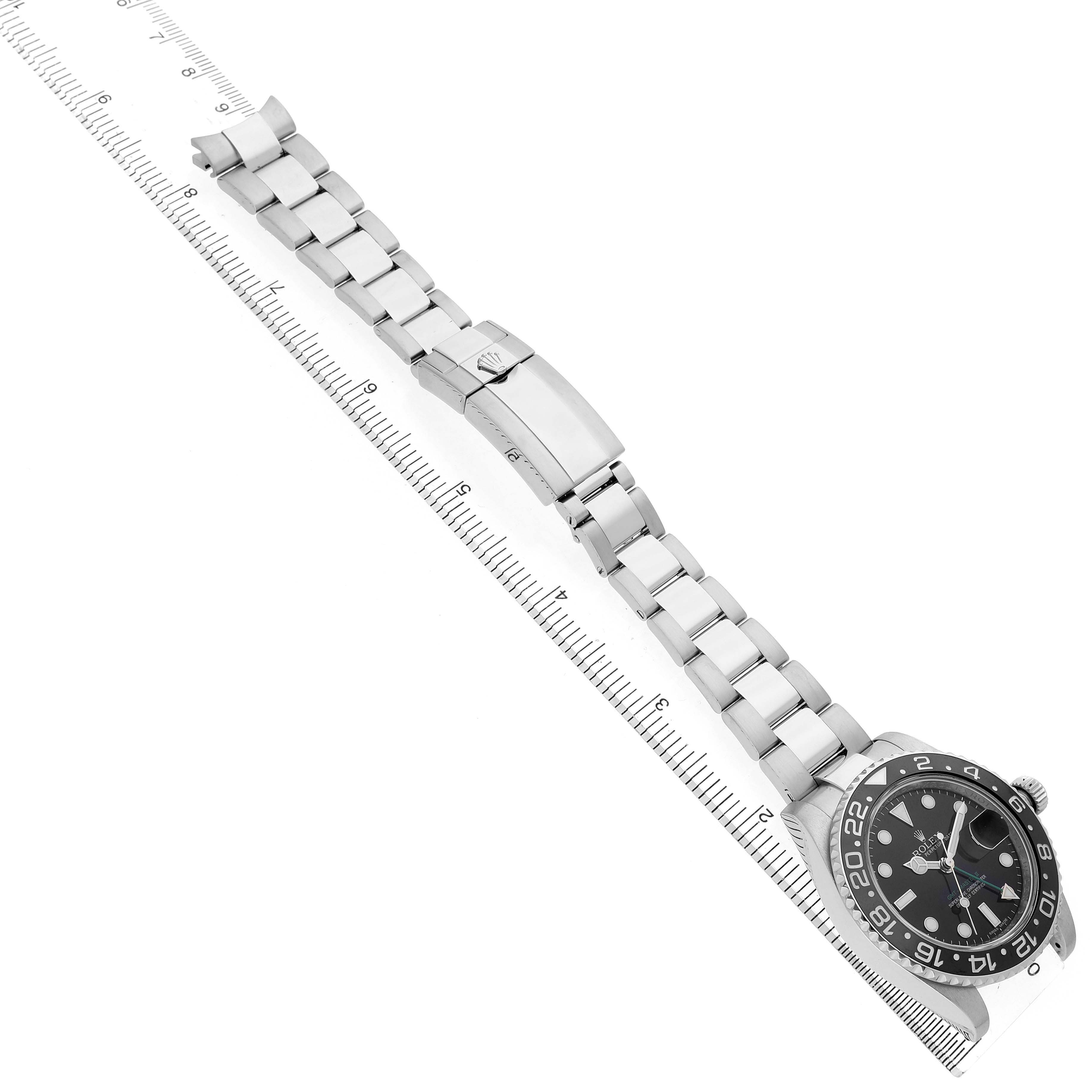 The Rolex GMT-Master 116710 Men's Stainless Steel Black Dial watch is shown at an angle, displaying the bracelet, clasp, case, and bezel alongside a ruler for scale.