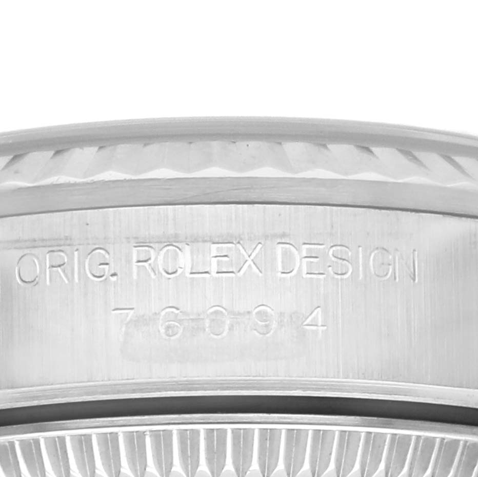 This image shows a close-up of the side of a Rolex Oyster Perpetual 76094 Women's Stainless Steel White Dial 76094 Women's Stainless Steel White Dial watch case with the engraved text "ORIG. ROLEX DESIGN 76094".