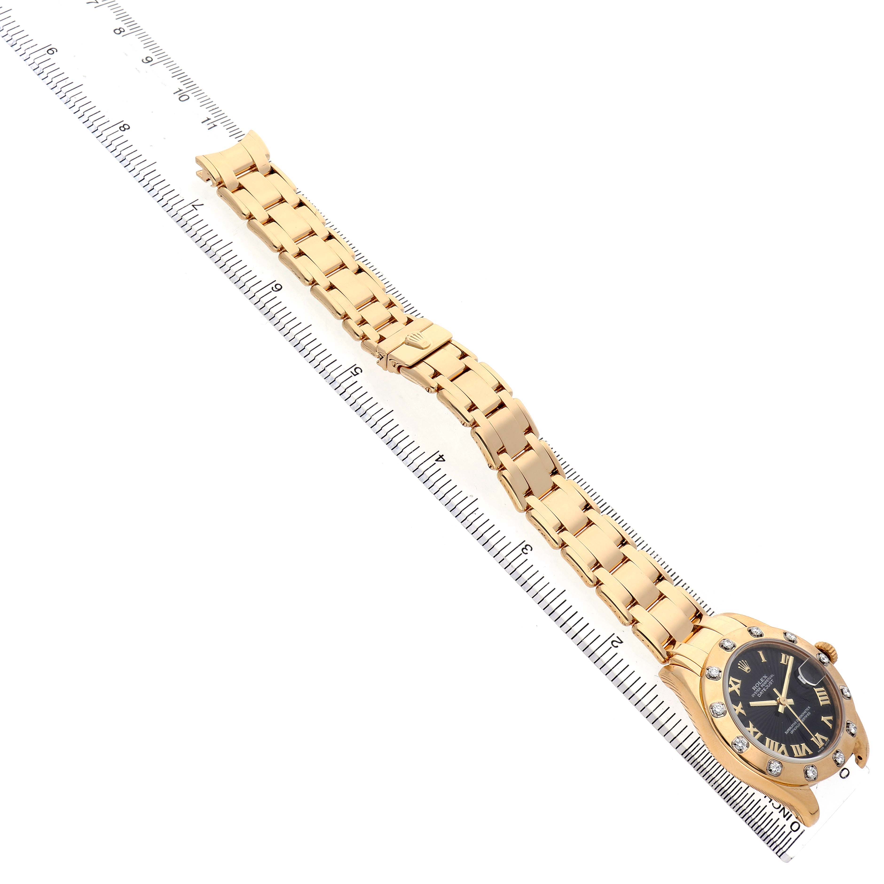 The image shows the Rolex Pearlmaster 81318 Women's Yellow Gold Black Dial watch laid flat at an angle, highlighting the bracelet and face with a ruler for scale.