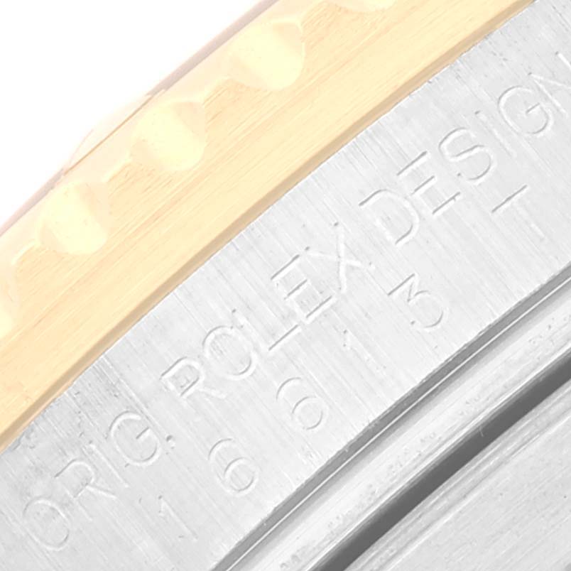 The image shows a close-up of the side view of the bezel and casing of a Rolex Submariner 16613 Men's Steel and Gold (two tone) Blue Dial 16613 Men's Steel and Gold (two tone) Blue Dial watch, revealing some engraved text.