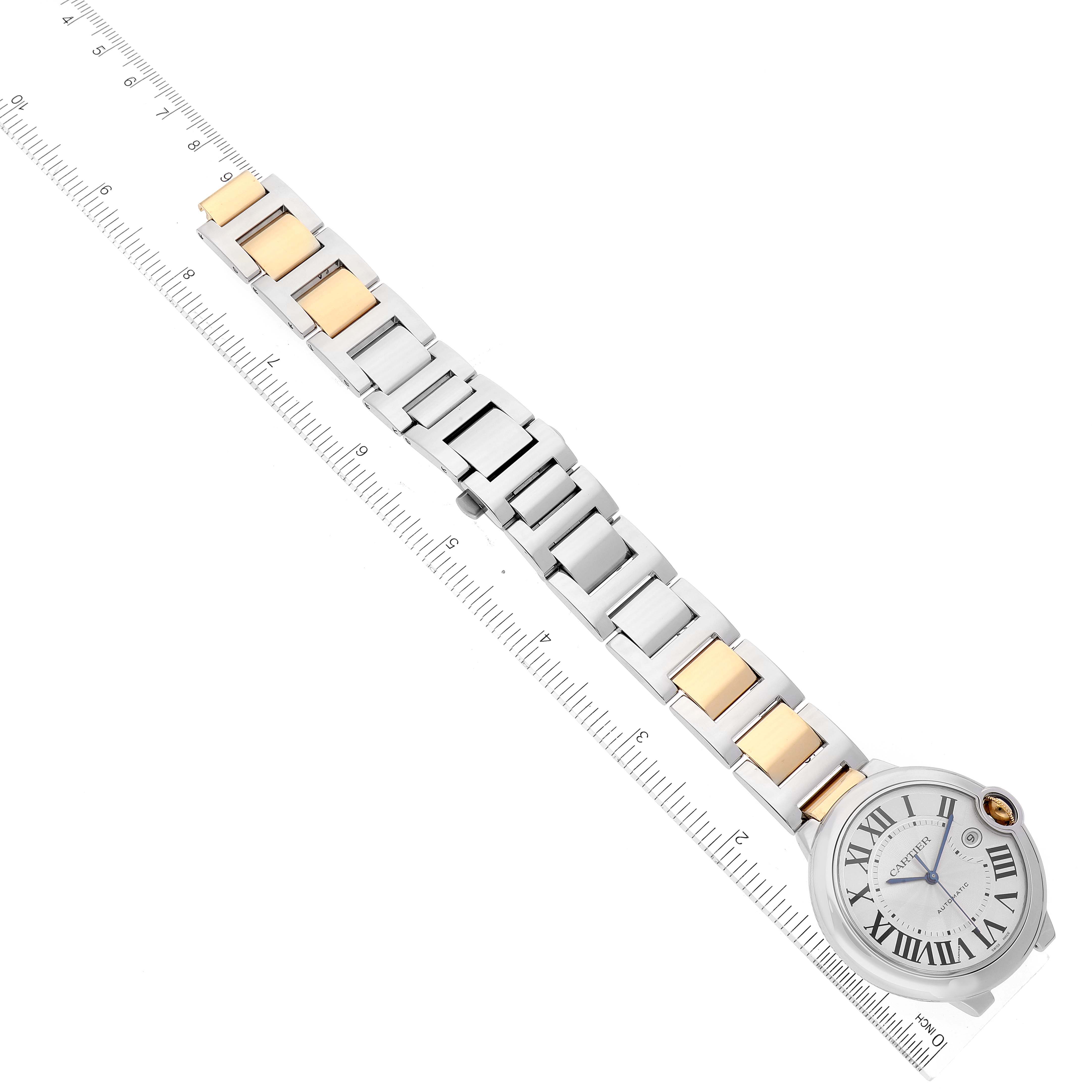 The image shows the Ballon Bleu watch by Cartier, highlighting its face and bi-metal bracelet, laid next to a ruler for scale.