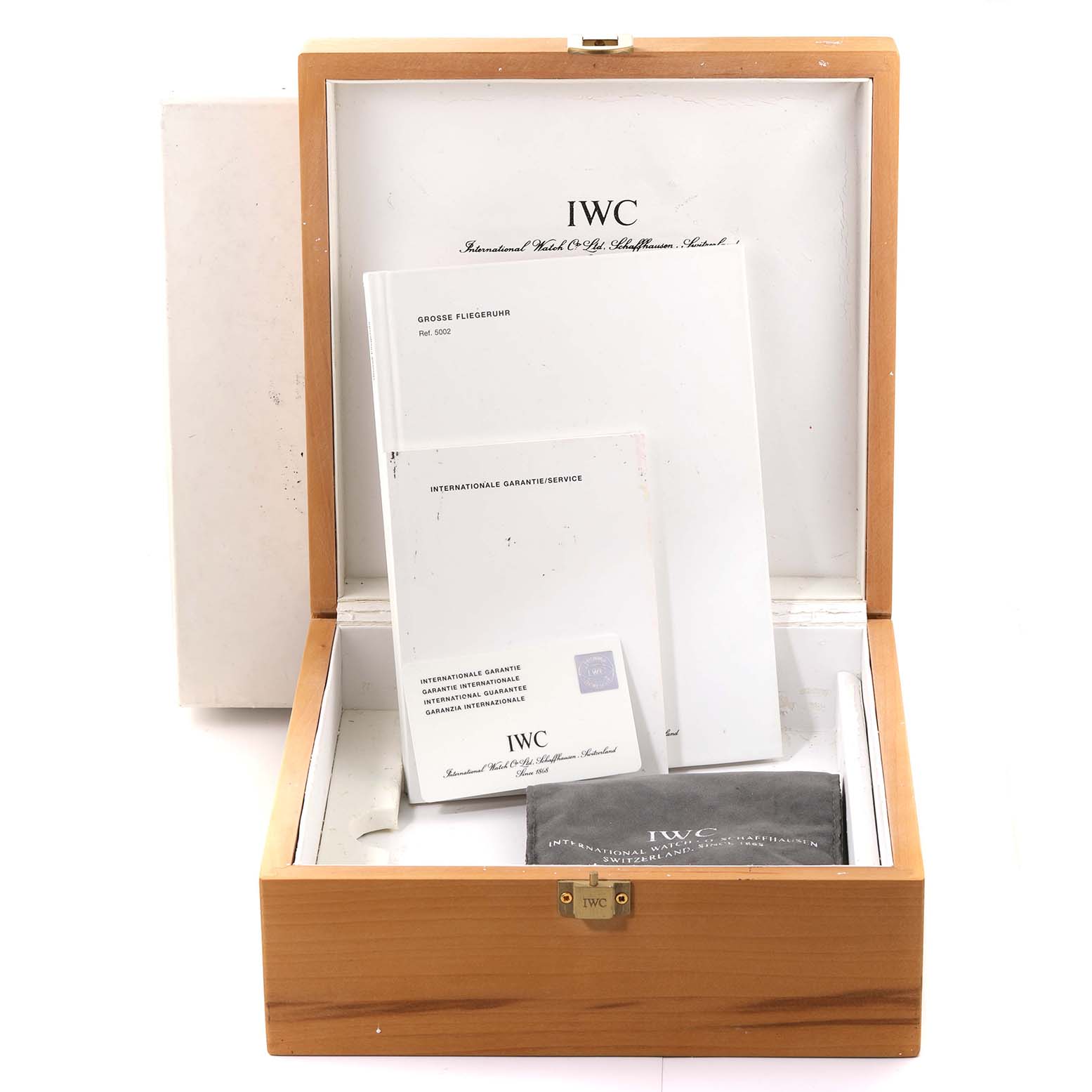 The image shows the opened box of the Pilot model by IWC, containing manuals and a microfiber cloth.