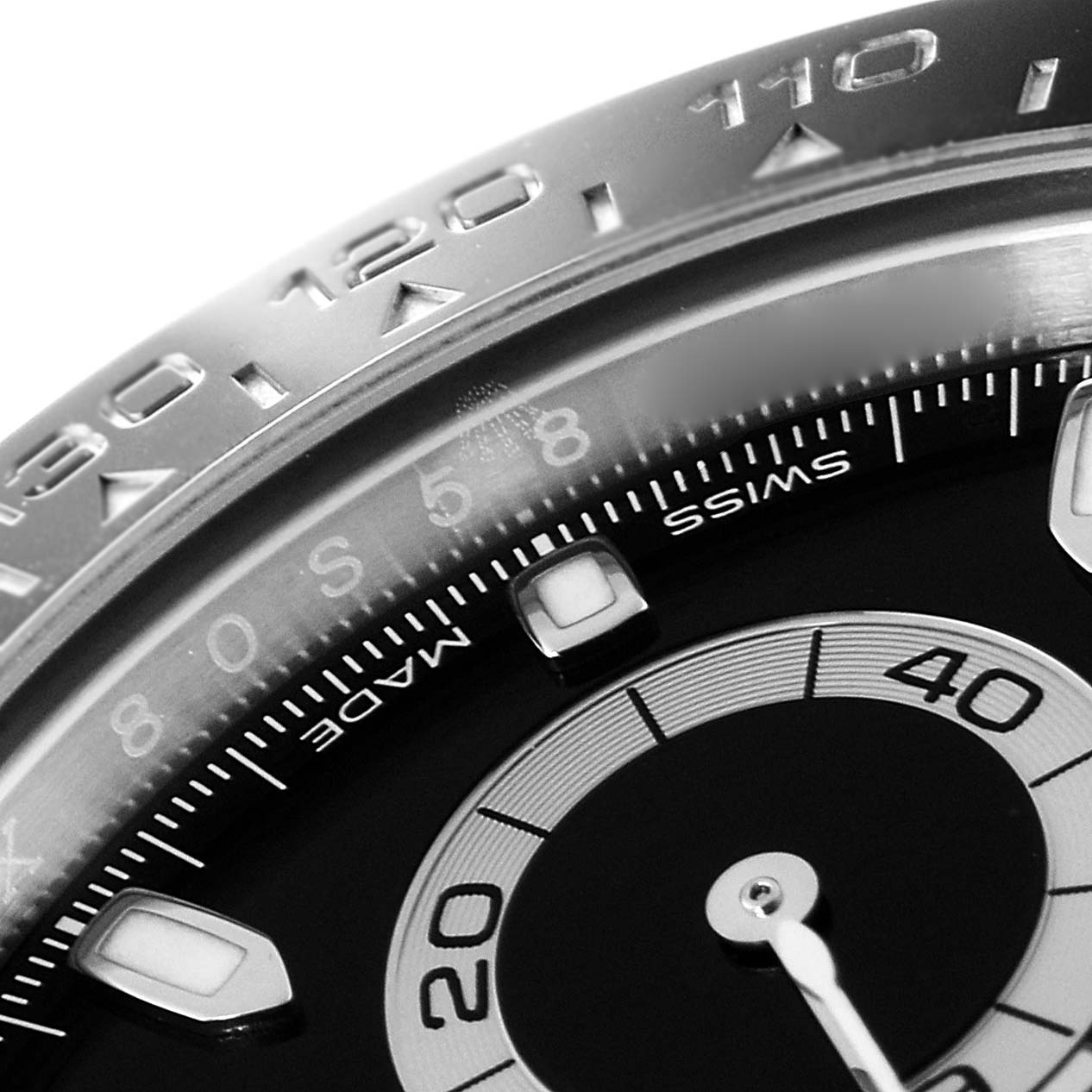 This close-up image of a Rolex Daytona 116500 Men's Stainless Steel Black Dial 116500 Men's Stainless Steel Black Dial shows part of the bezel, chapter ring, and sub-dial.