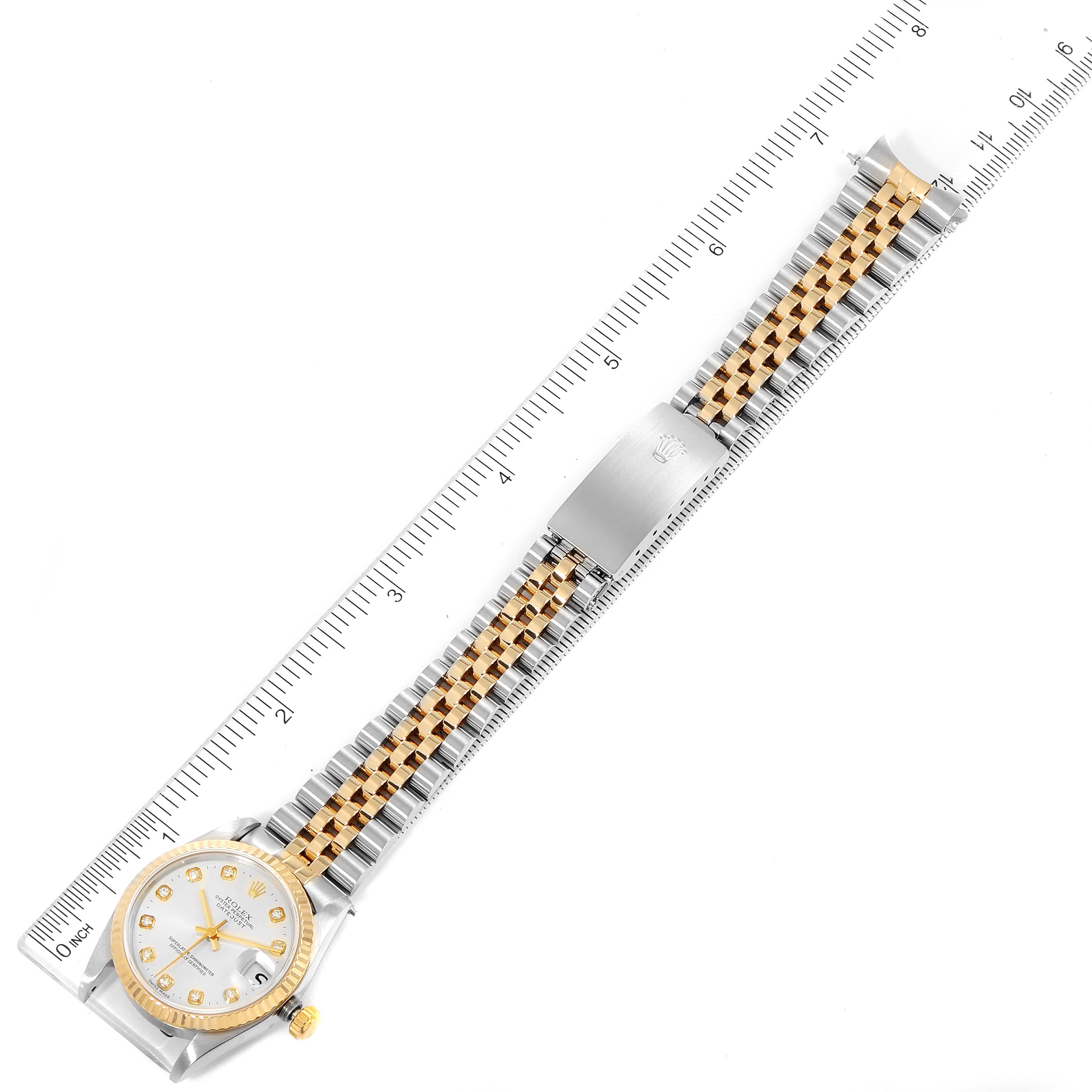 The image shows a Mid-Size Rolex watch laid flat with a ruler alongside it, displaying its full bracelet and dial from a top-down angle.