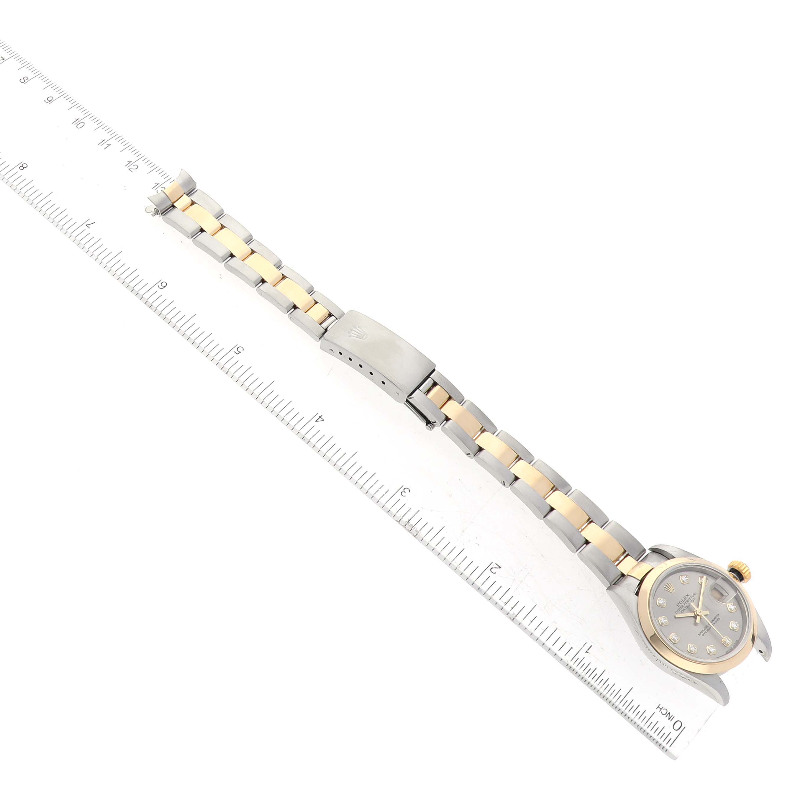 The image shows a Rolex Datejust 79163 Women's Steel and Gold (two tone) Grey Dial 79163 Women's Steel and Gold (two tone) Grey Dial watch from an overhead angle, highlighting its bracelet, clasp, and face next to a ruler.