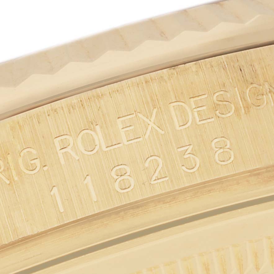 The image shows a close-up of the side engraving on a Rolex President 118238 Men's Yellow Gold Brown Dial 118238 Men's Yellow Gold Brown Dial model watch, displaying the serial number and part of the bezel.