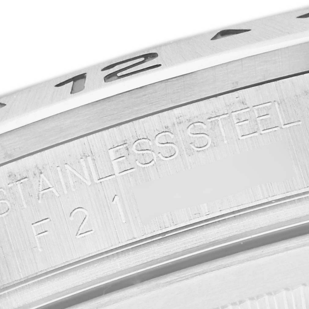 The image depicts a close-up view of the bezel and case side of a Rolex Explorer 16570 Men
s Stainless Steel Black Dial 16570 Men
s Stainless Steel Black Dial watch, showing the "stainless steel" engraving.