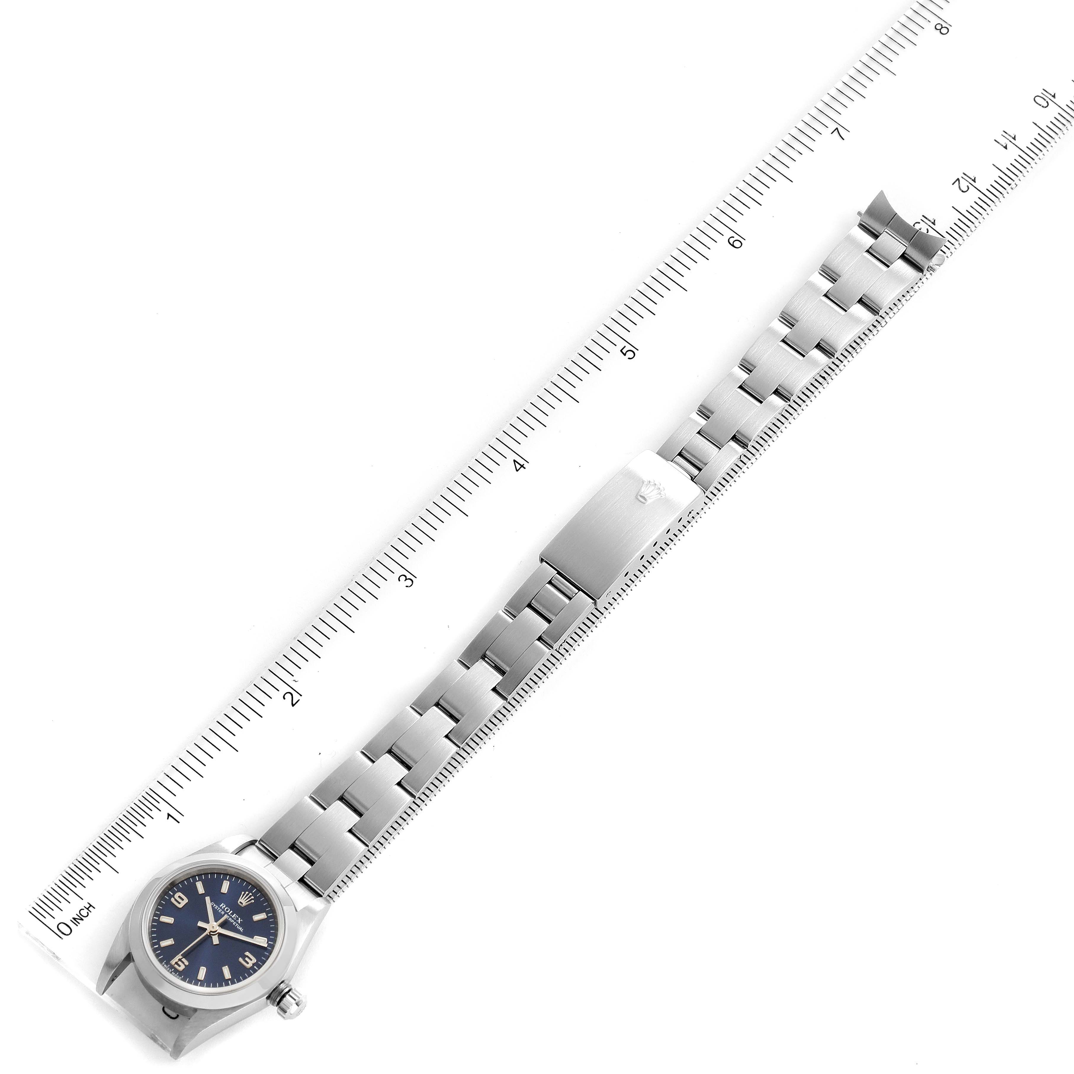 This image shows a Rolex Oyster Perpetual 76080 Women
s Stainless Steel Blue Dial 76080 Women
s Stainless Steel Blue Dial watch from a top-down angle, featuring the entire wristband and the watch face against a measuring ruler.