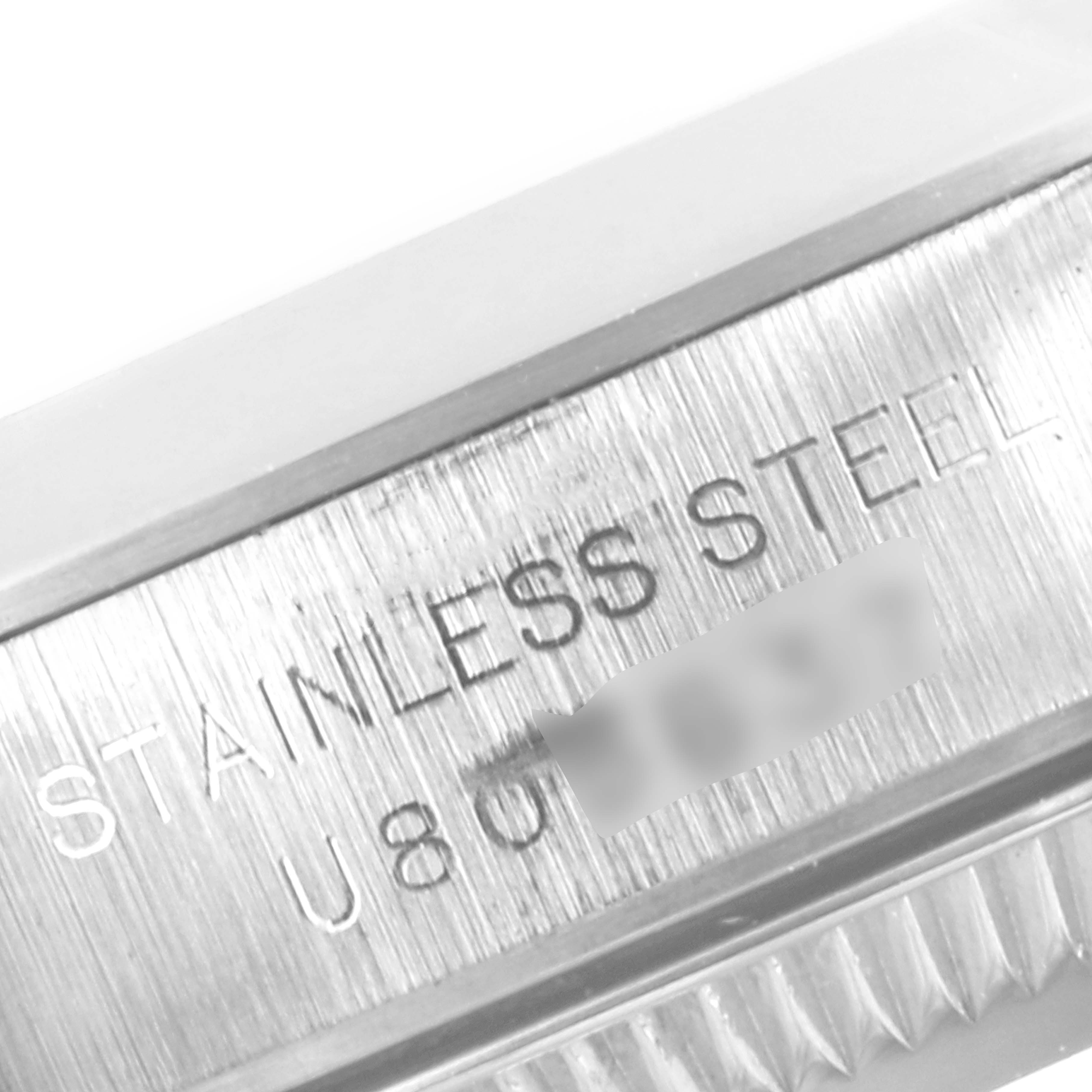 This image shows a close-up of the stainless steel case's model and serial number on a Rolex Oyster Perpetual 67180 Women's Stainless Steel Black Dial 67180 Women's Stainless Steel Black Dial watch.