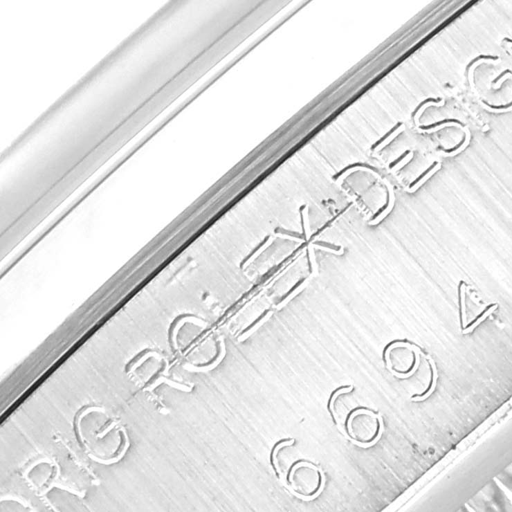 The image shows an angled close-up of the side of a Rolex Vintage Collection 6694 Men's Stainless Steel Silver Dial 6694 Men's Stainless Steel Silver Dial watch with engraved text.