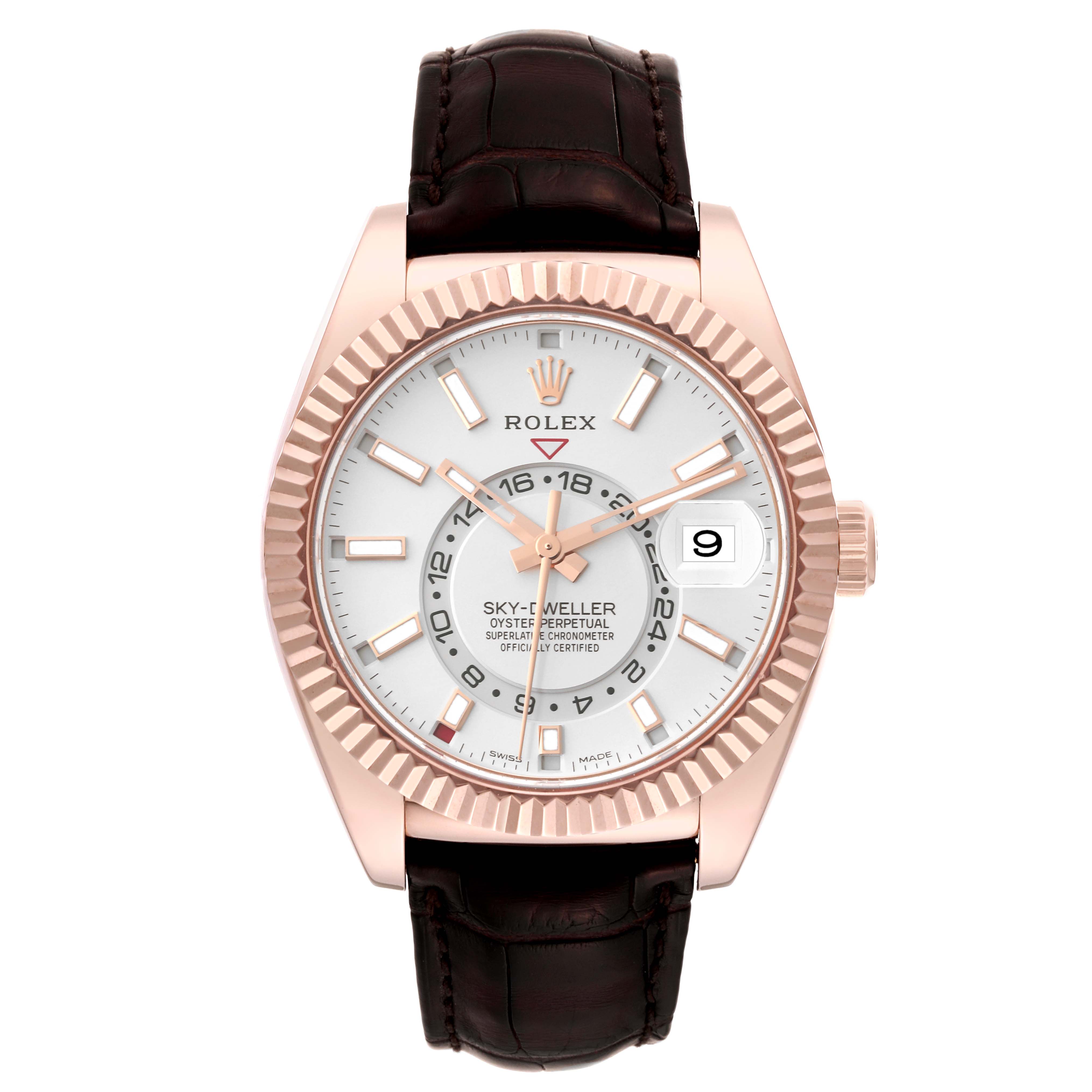 The image shows a front view of the Rolex Sky-Dweller model 326135 men's watch, featuring its white dial, gold fluted bezel, and leather strap.