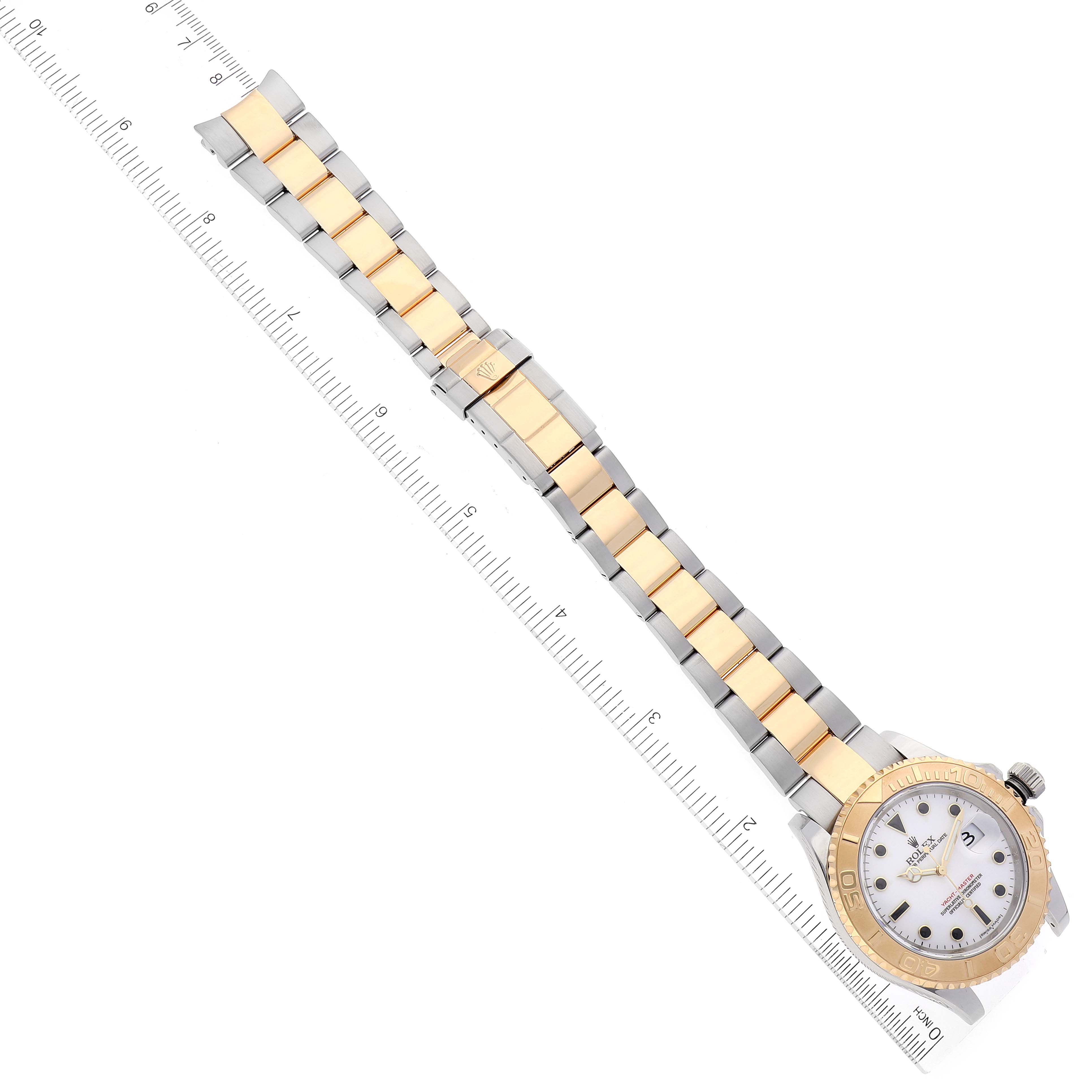 The Rolex Yacht-Master 16623 Men
s Steel and Gold (two tone) White Dial 16623 Men
s Steel and Gold (two tone) White Dial watch is shown from a top-down angle, displaying the full bracelet and face beside a ruler for scale.