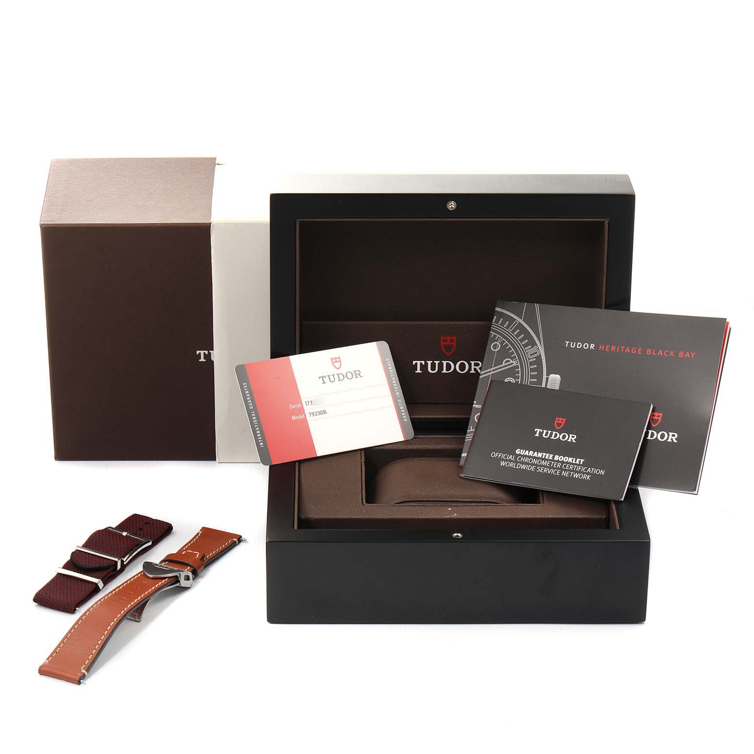 The image shows a Tudor Heritage Black Bay 79230R Men
s Stainless Steel Black Dial 79230R Men
s Stainless Steel Black Dial watch box, warranty cards, strap accessories, and instruction booklets.