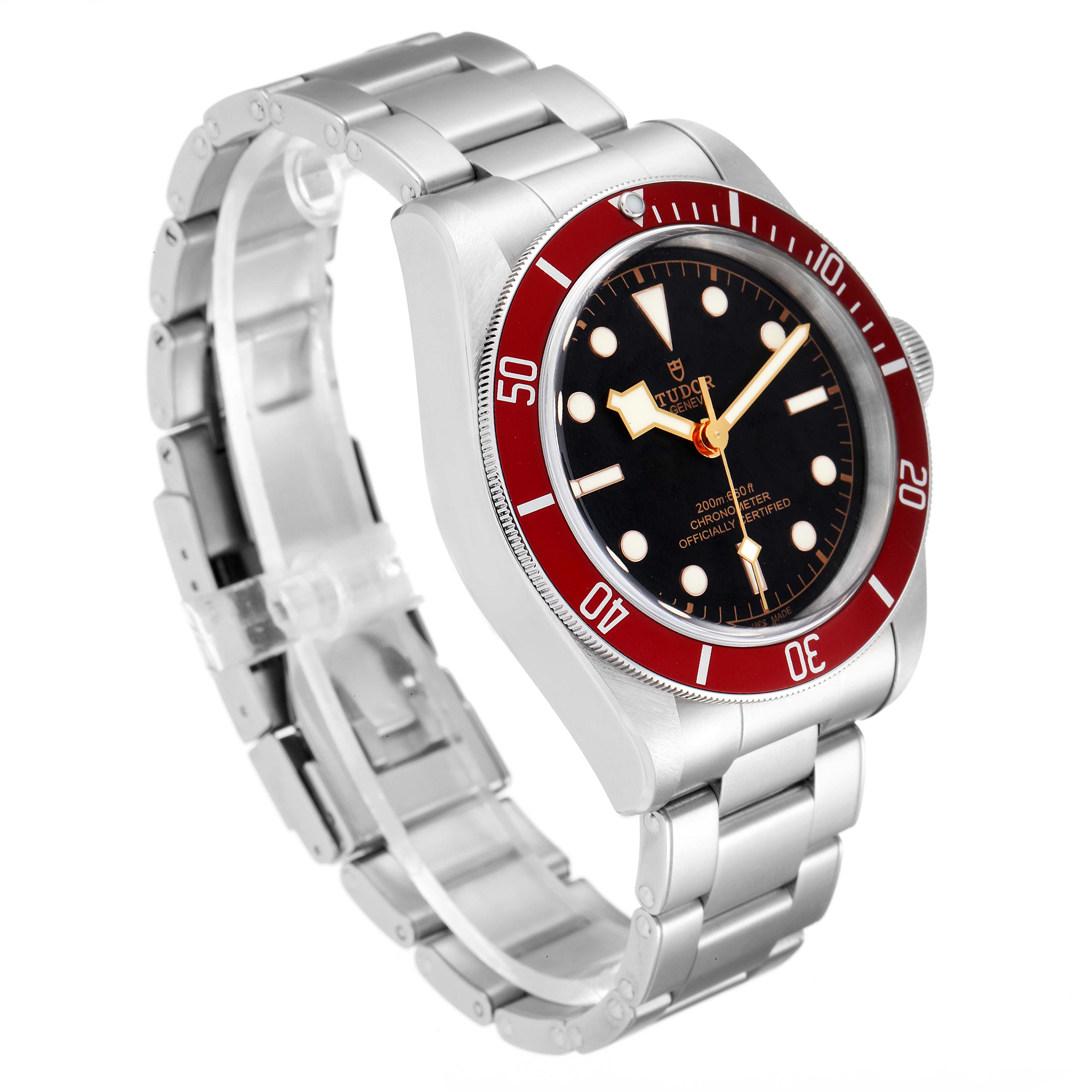 The image shows a Tudor Heritage Black Bay 79230R Men
s Stainless Steel Black Dial 79230R Men
s Stainless Steel Black Dial watch at a three-quarter angle, detailing its stainless steel bracelet, black dial, and red bezel.