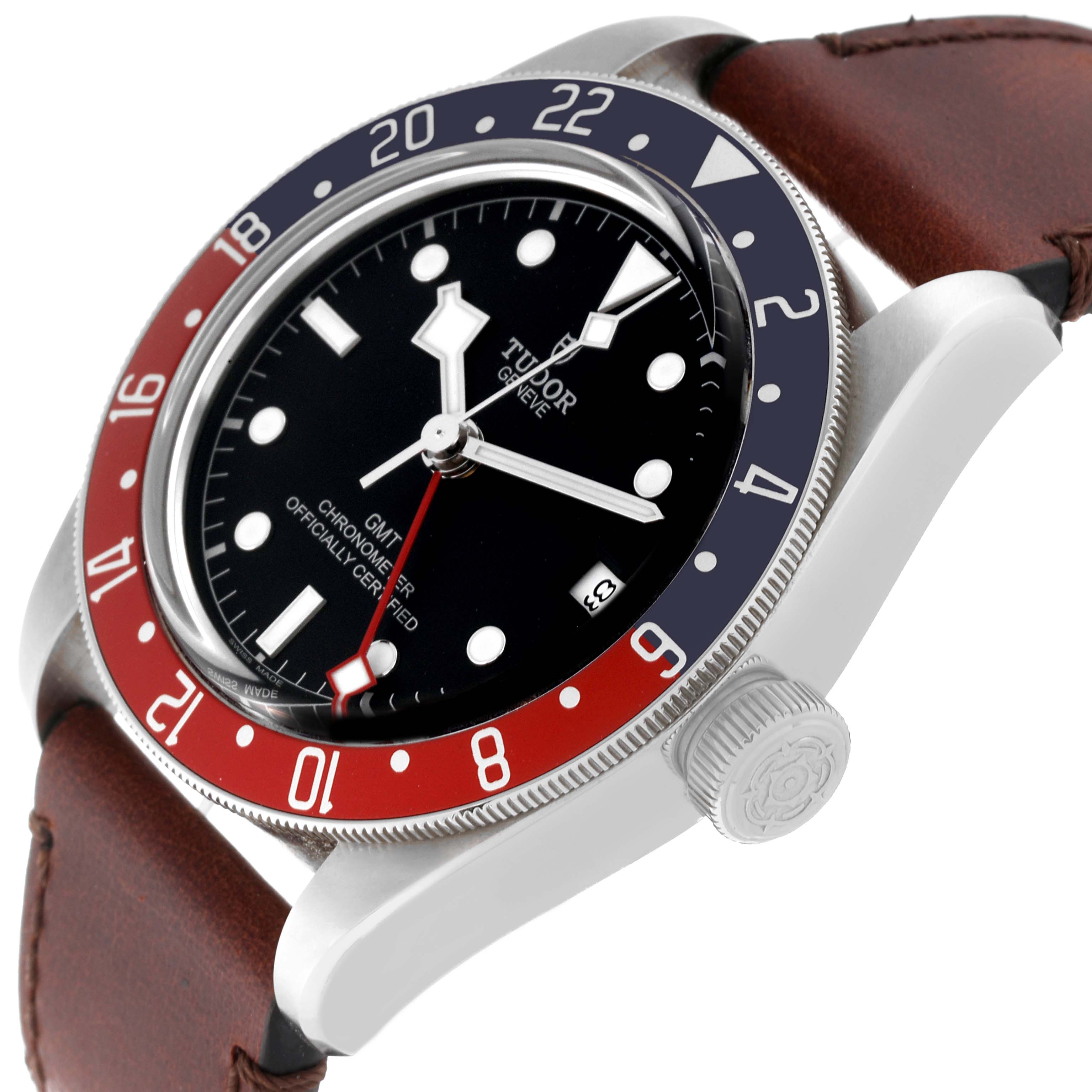 The image shows a Heritage Black Bay GMT watch by Tudor at an angle highlighting the dial, bezel, crown, and brown leather strap.