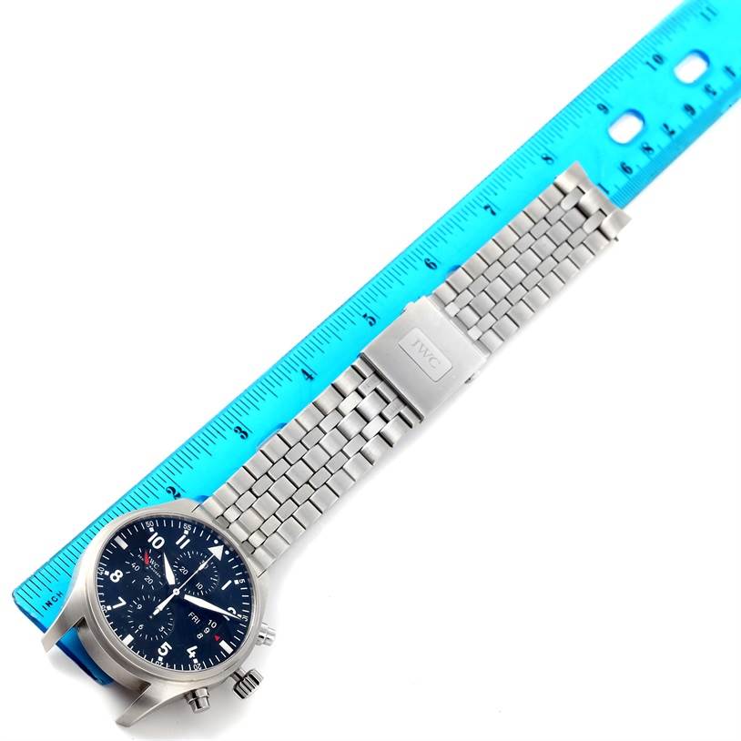 The image shows an IWC Pilot IW377704 Men's Stainless Steel Black Dial IW377704 Men's Stainless Steel Black Dial model watch lying flat next to a ruler, displaying its face, case, and metal bracelet.