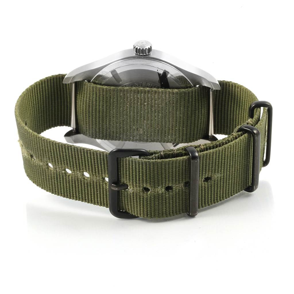 The image shows the back view of an IWC Pilot IW327011 Men's Stainless Steel Black Dial IW327011 Men's Stainless Steel Black Dial model watch featuring an olive green fabric strap and metal clasp.