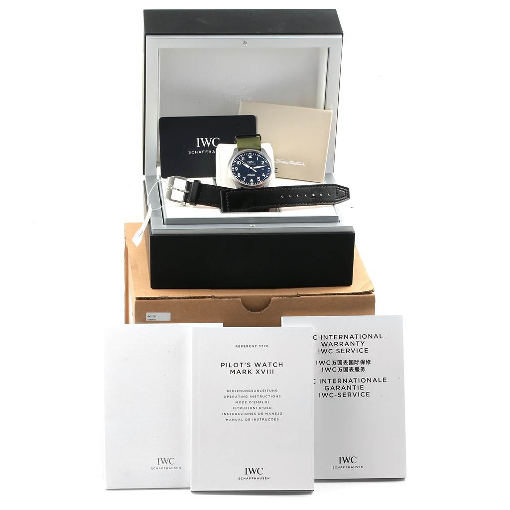 The image shows an IWC Pilot IW327011 Men's Stainless Steel Black Dial IW327011 Men's Stainless Steel Black Dial's Watch Mark XVIII in its box, along with instruction booklets and warranty cards displayed in front.