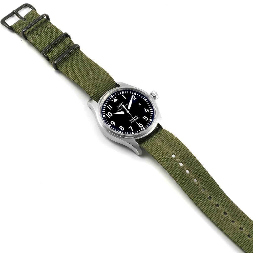 The IWC Pilot IW327011 Men's Stainless Steel Black Dial IW327011 Men's Stainless Steel Black Dial model watch is displayed at an angle showing its face, case, and green fabric strap with buckle.